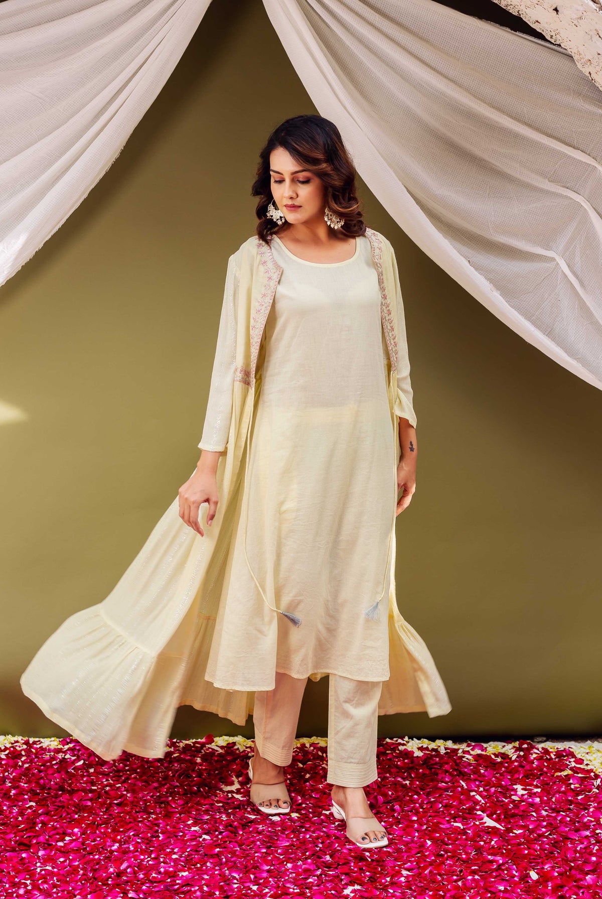 Female model wearing a shimmery cream jacket-style kurta with delicate pink printed borders.