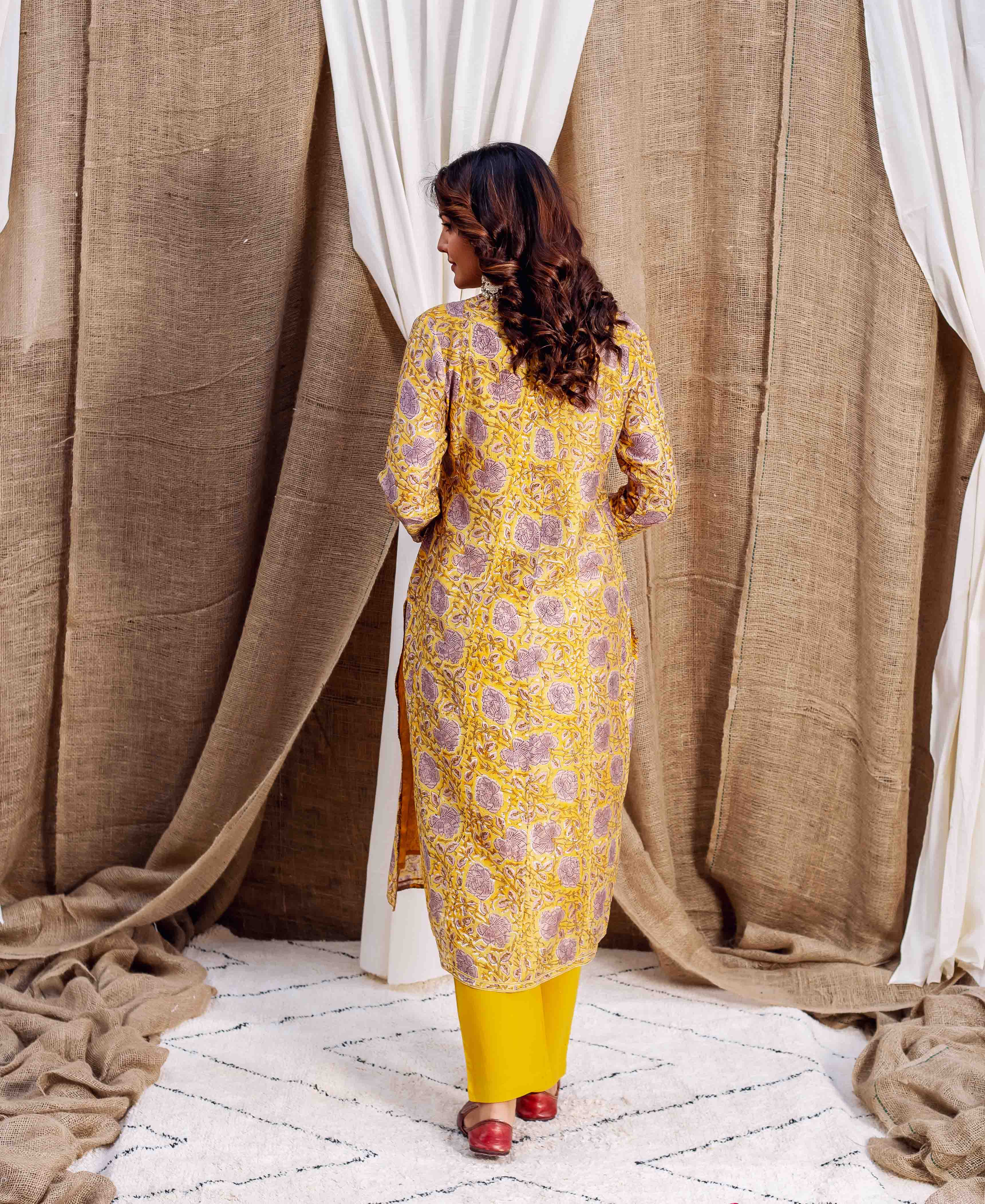 A woman in a yellow and purple floral print kurta, facing away from the camera.