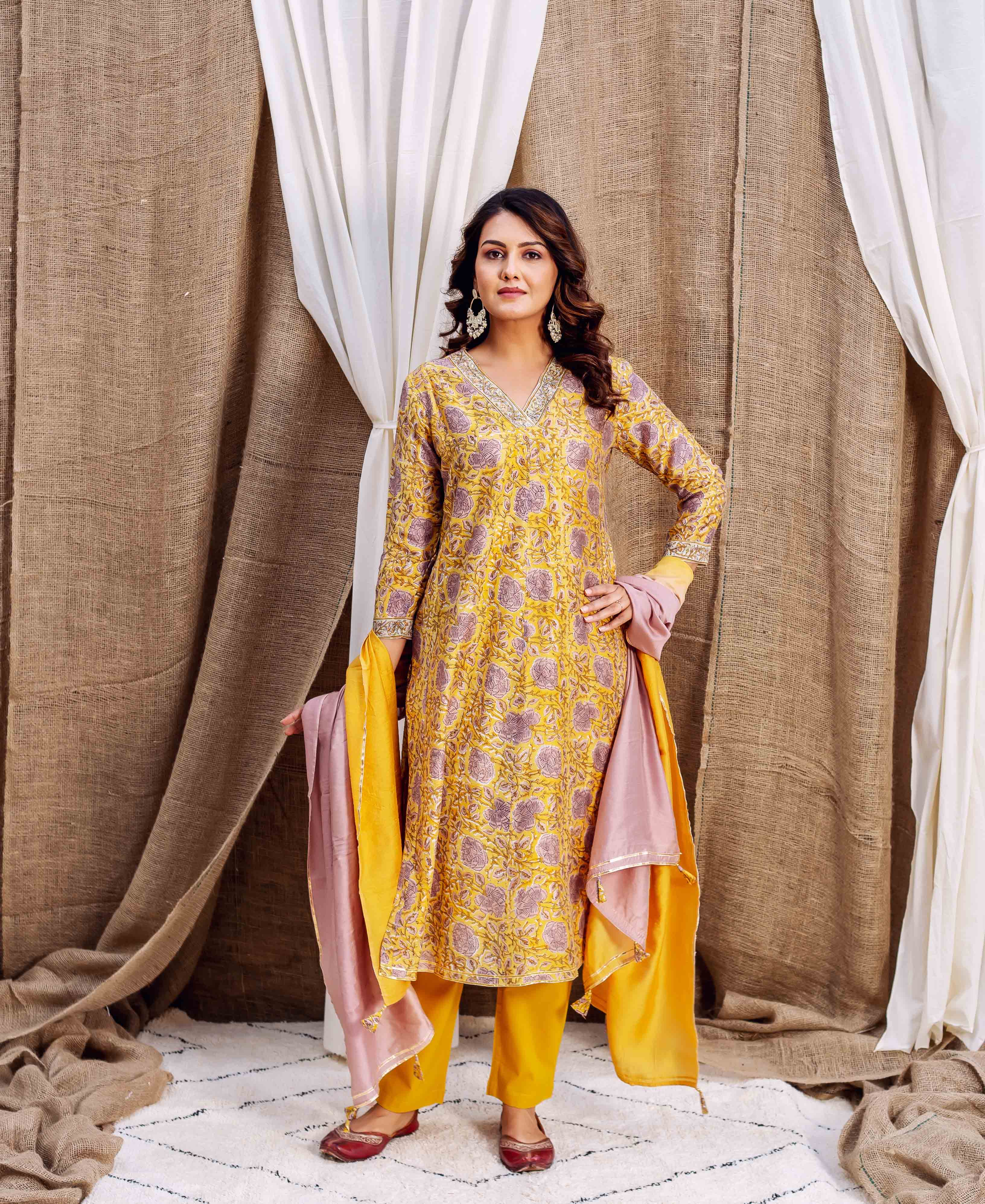 A model wearing a yellow and pink floral printed kurta with matching pants and dupatta.