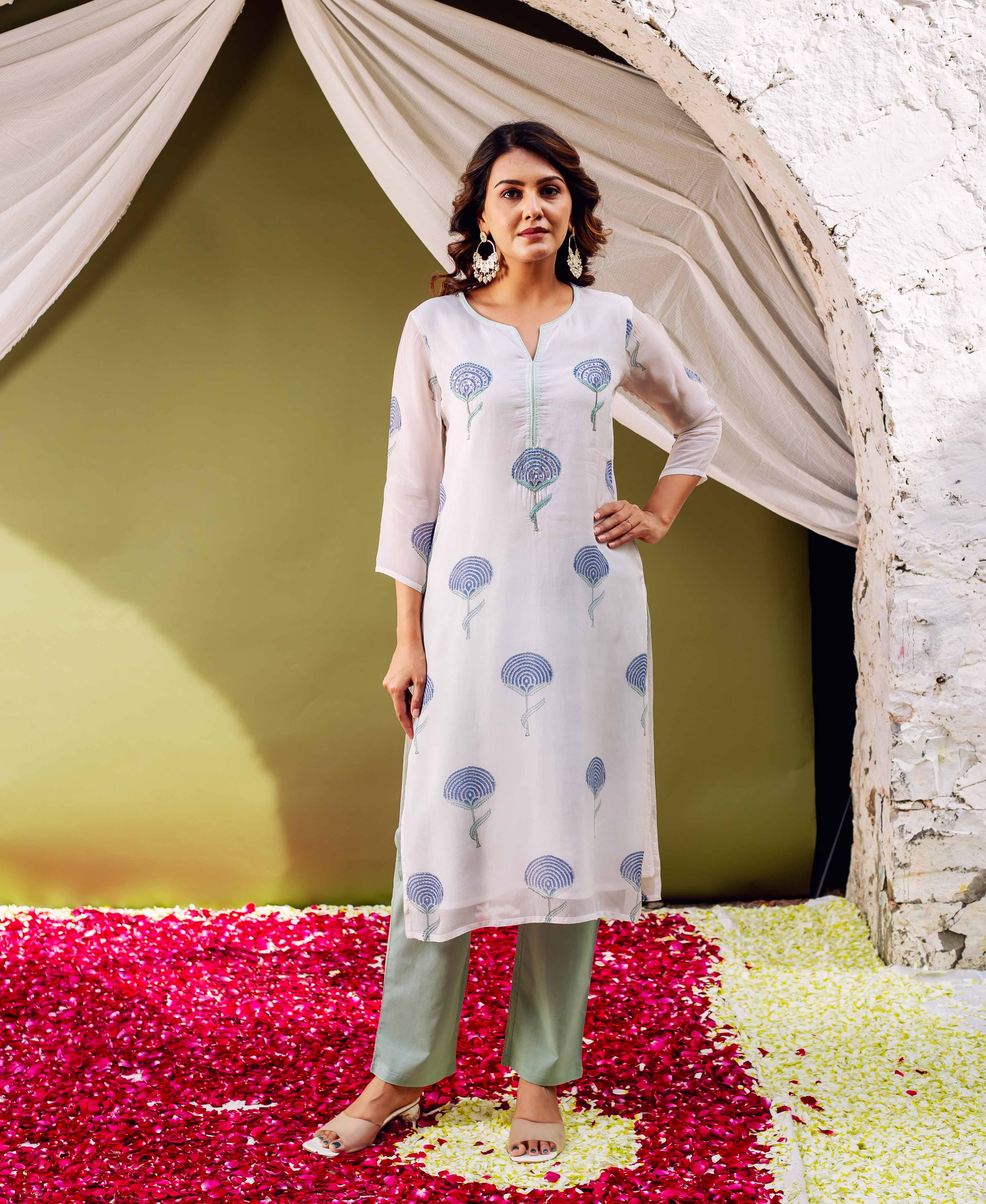 Woman standing in a white hand block printed organza kurta with blue motifs and sage pants.
