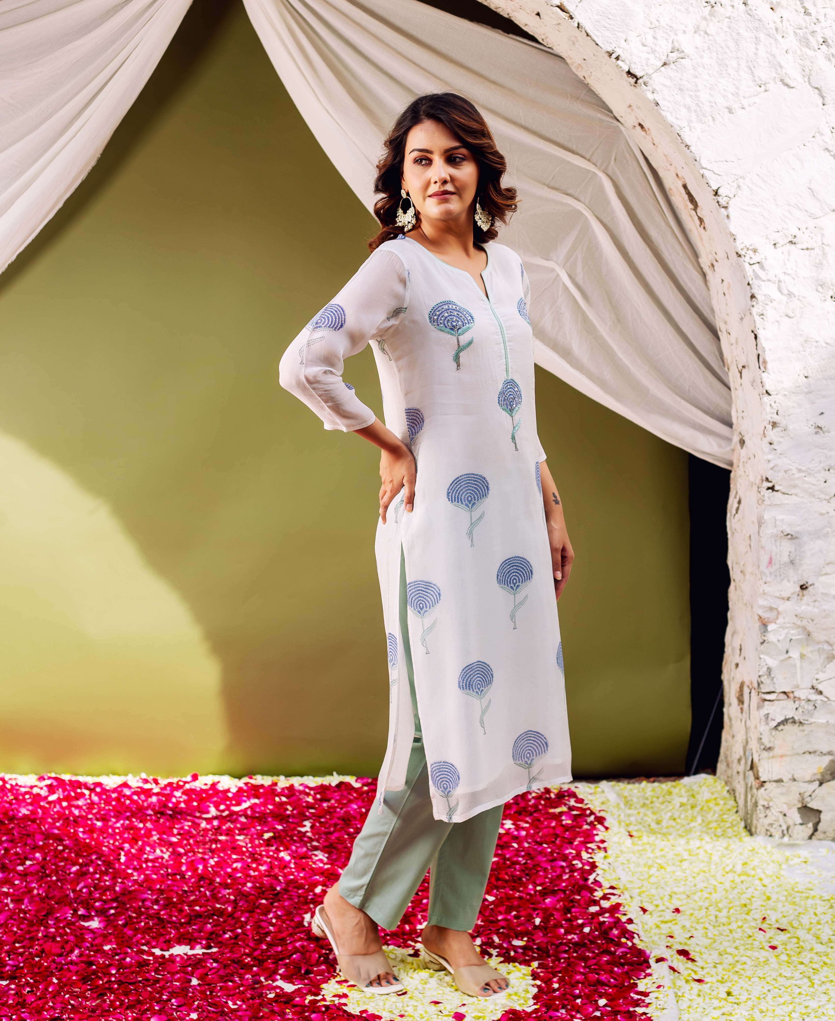 Model in white hand block printed organza kurta, blue floral motifs, and light green pants.
