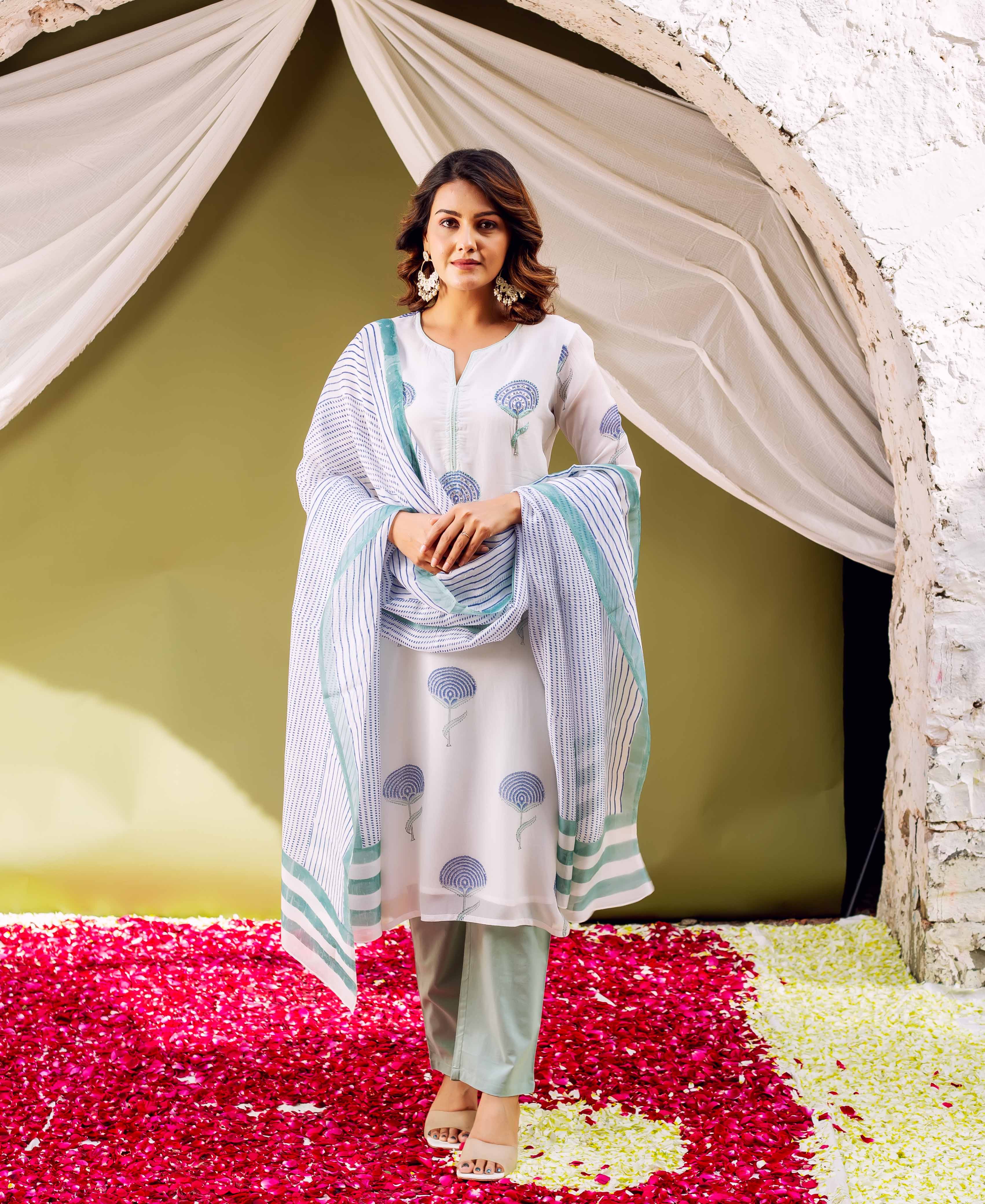 Model in white hand block printed organza kurta, blue floral prints, striped dupatta, green pants.