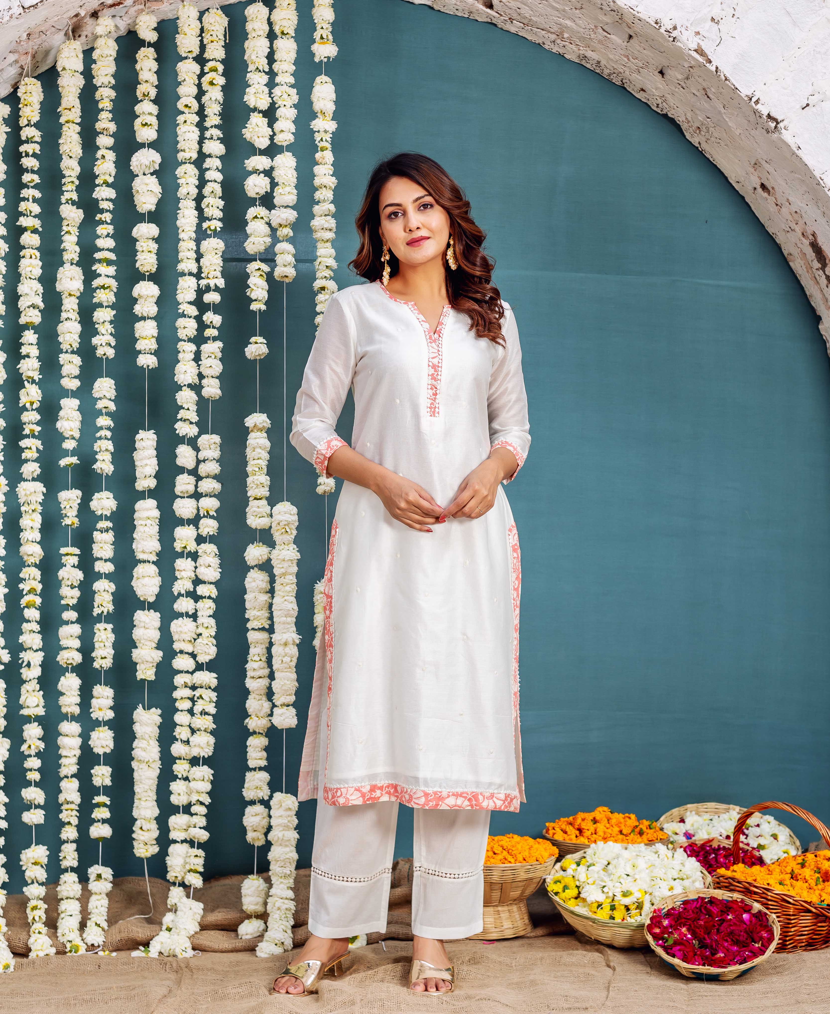 White hand-block printed kurta set with coral floral patterns, worn by a woman.