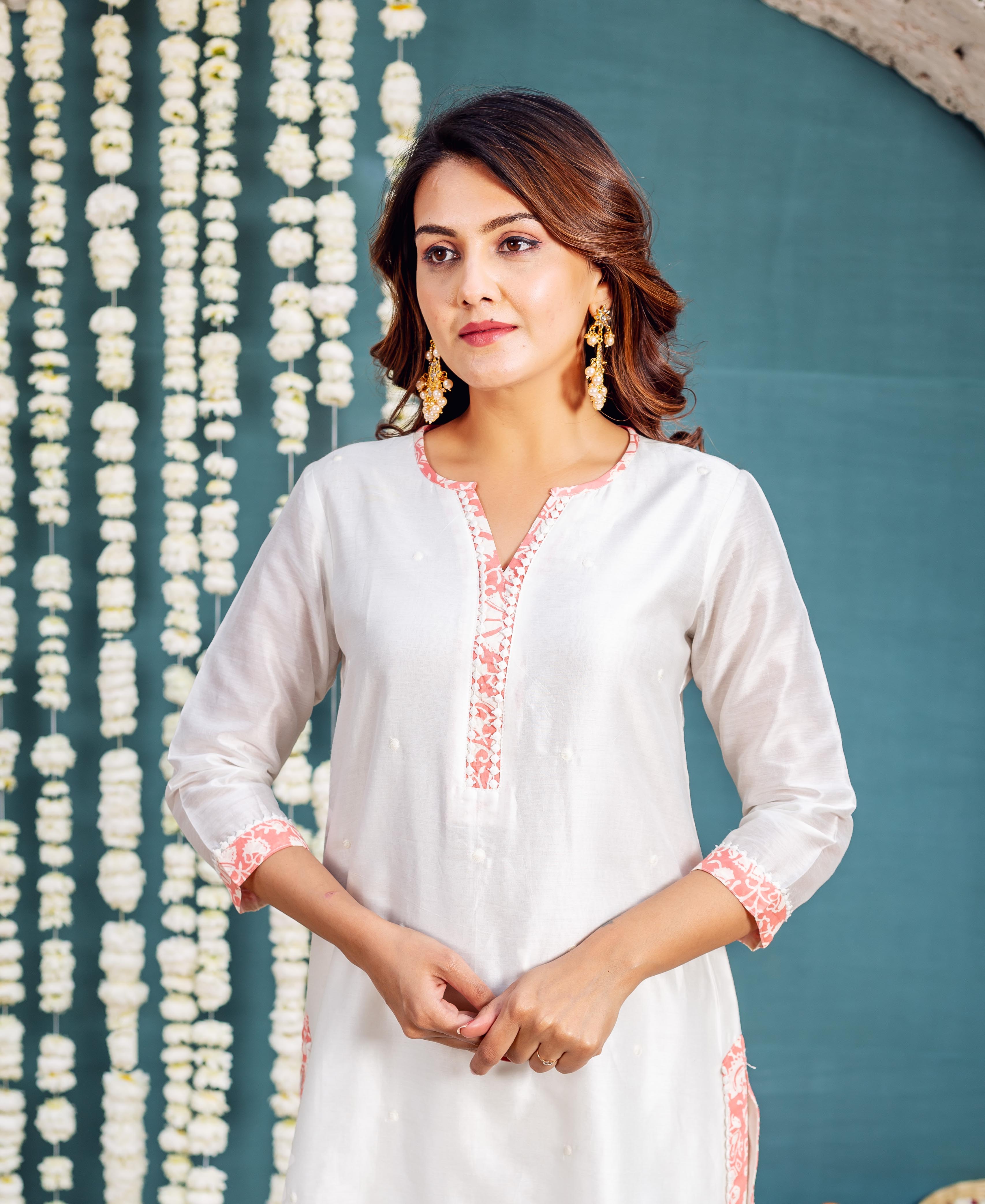 Front view model wearing white kurta with coral floral print on V-neck and cuffs.