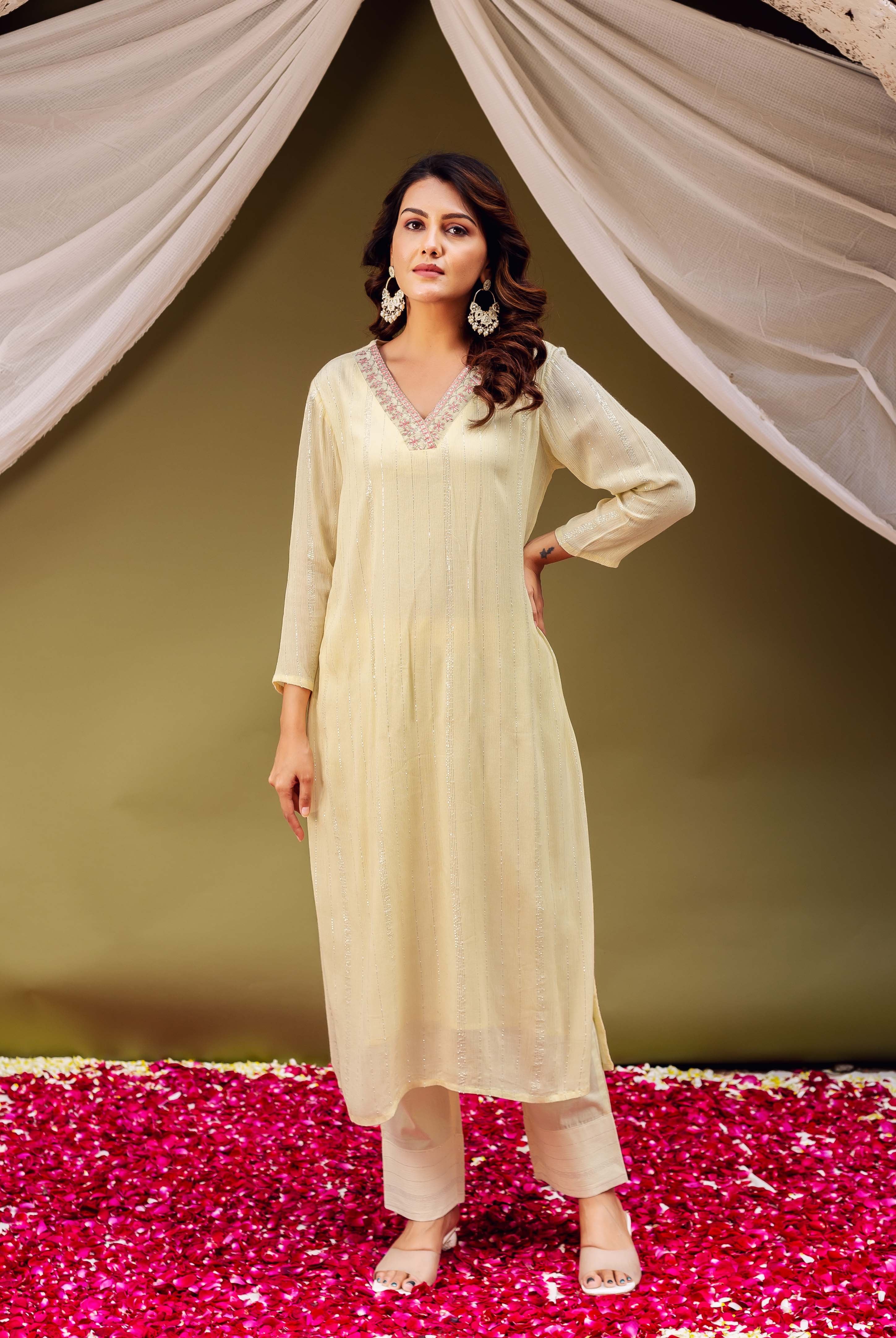 A woman in a lemon yellow kurta with intricate embroidery and block print.