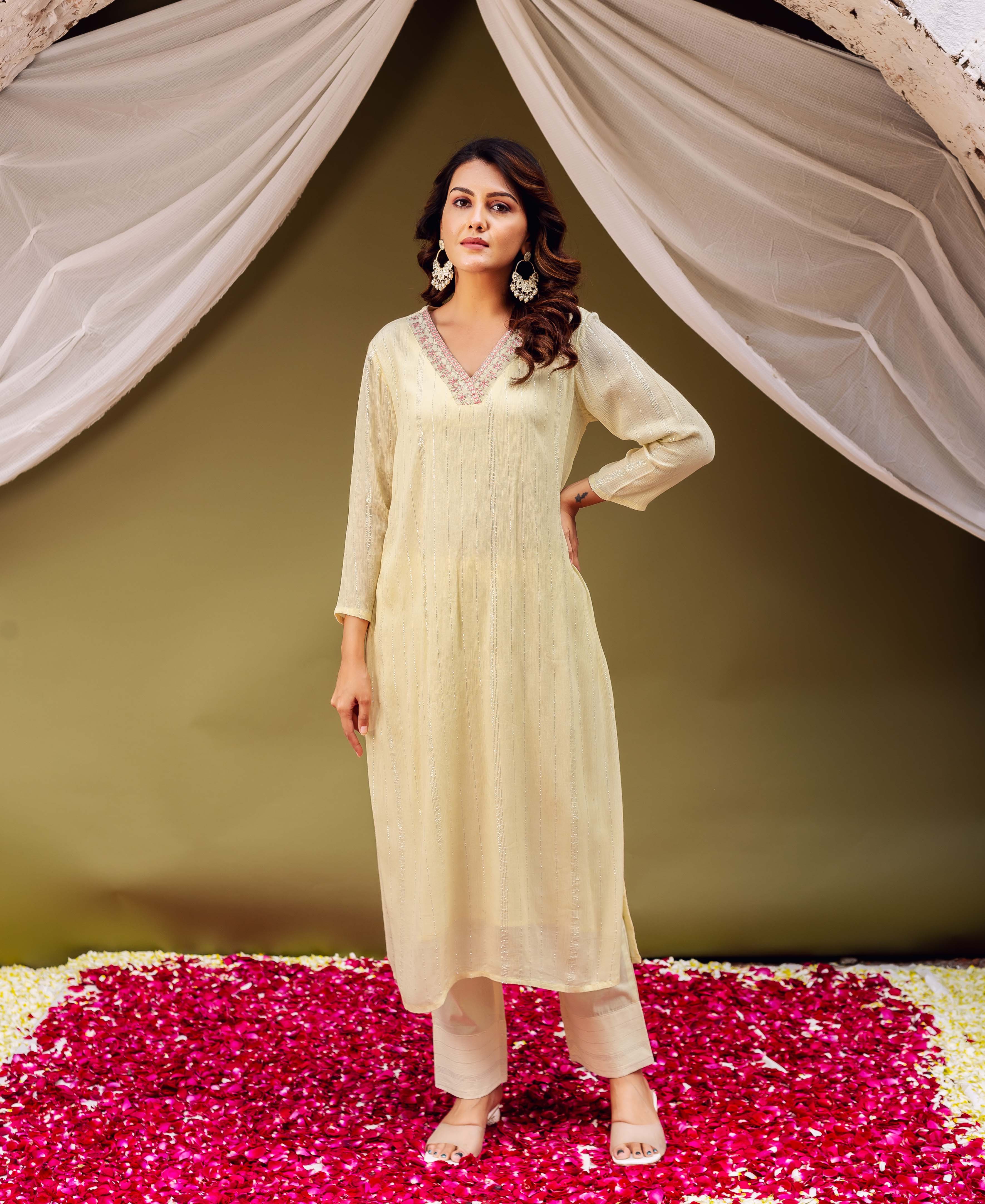 A woman in a lemon yellow kurta with intricate embroidery and block print.