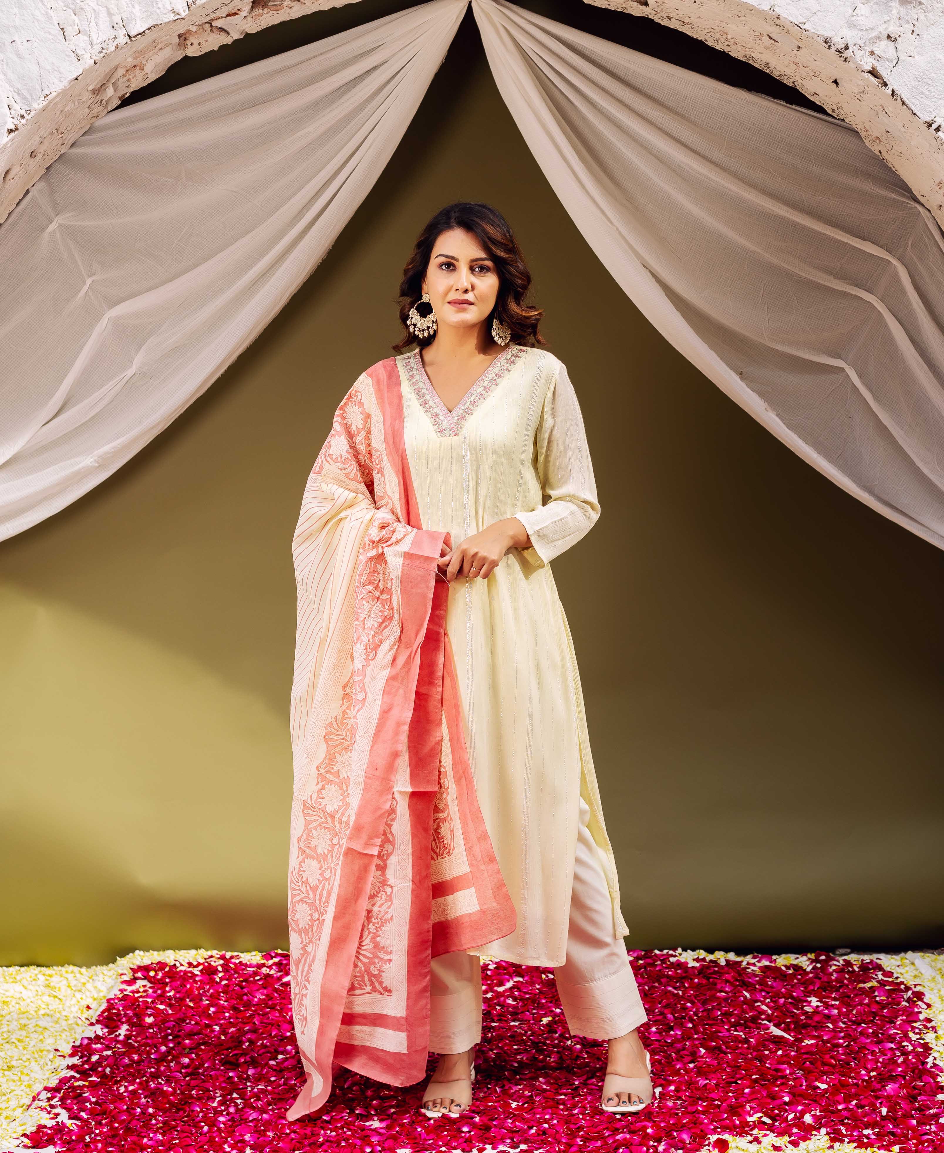 A woman in a lemon yellow kurta with pink embroidery and a matching dupatta.