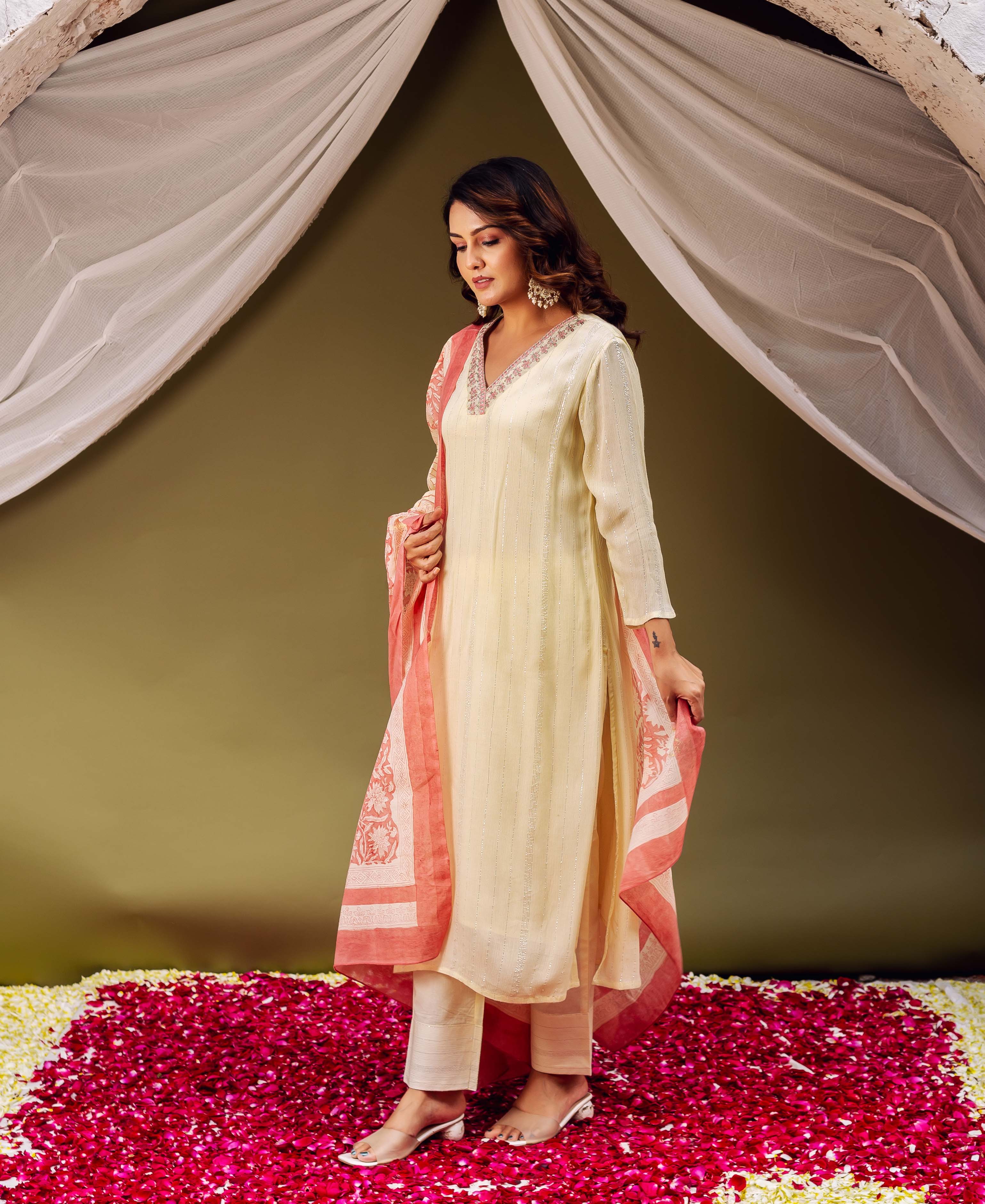 Model wearing a lemon yellow embroidered kurta and pants, with a coral block-printed dupatta.