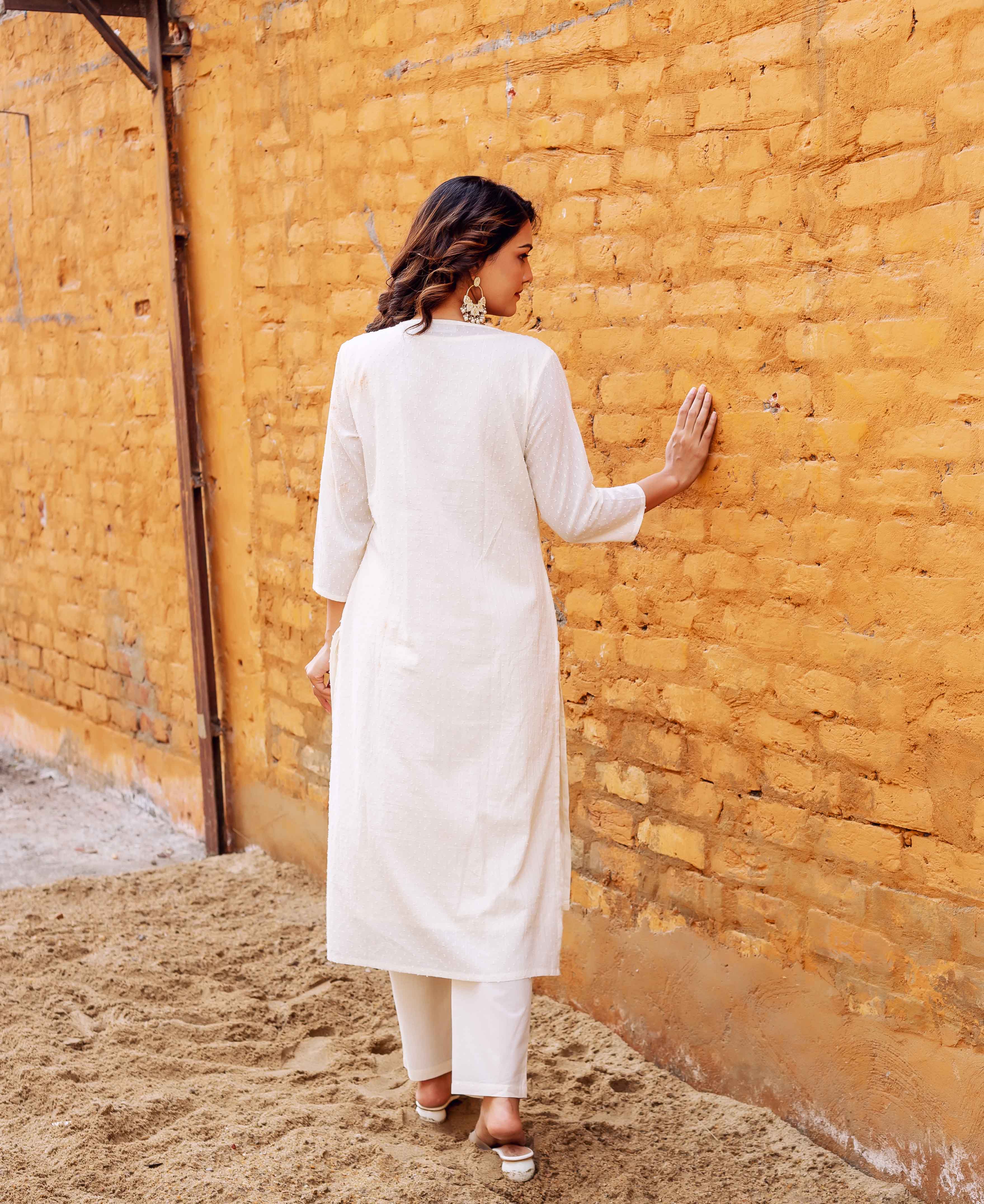 Back view of woman in lustrous ivory jacquard kurta and matching pants.