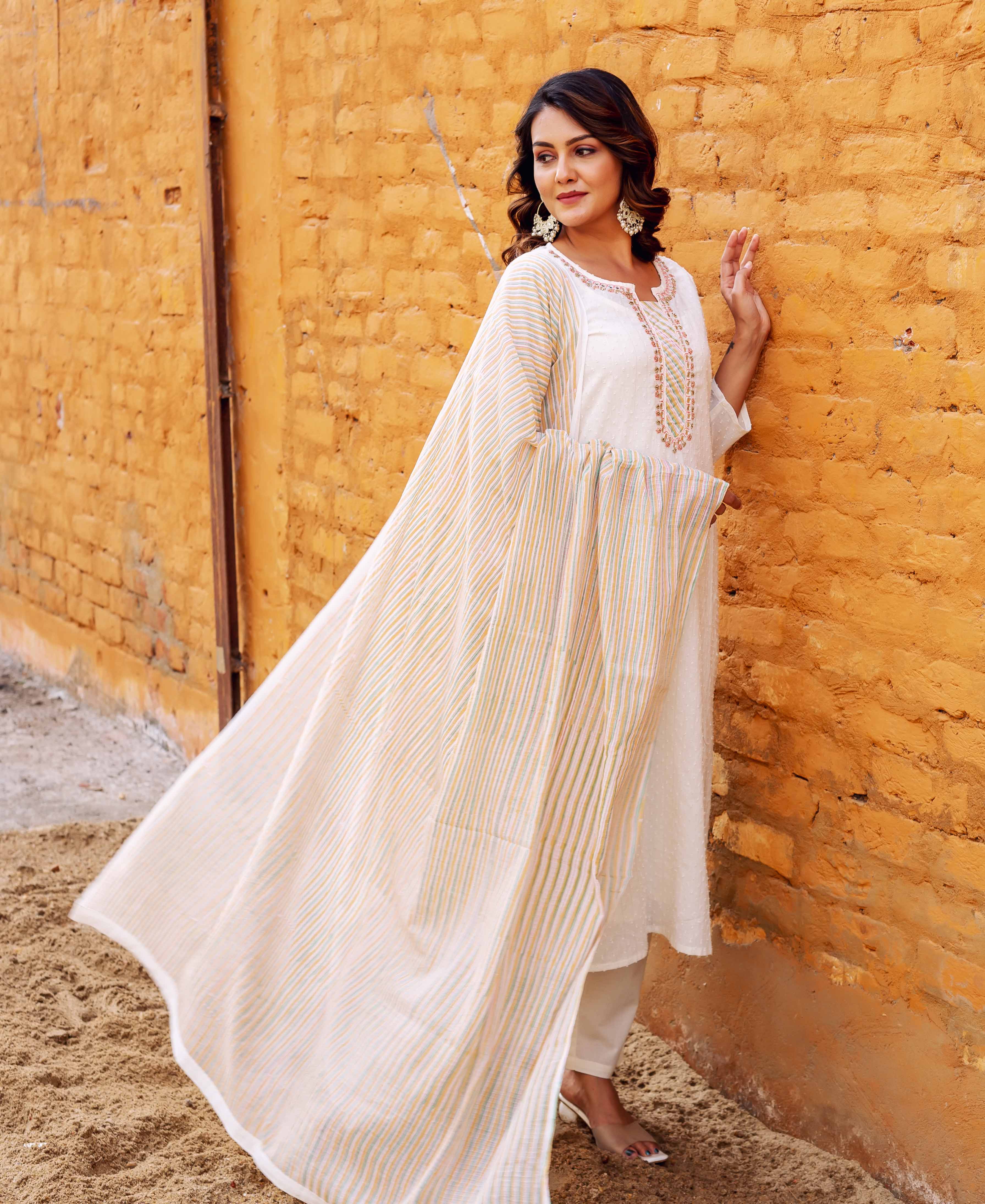 A model wearing a white kurta with intricate gold embroidery and a striped dupatta.