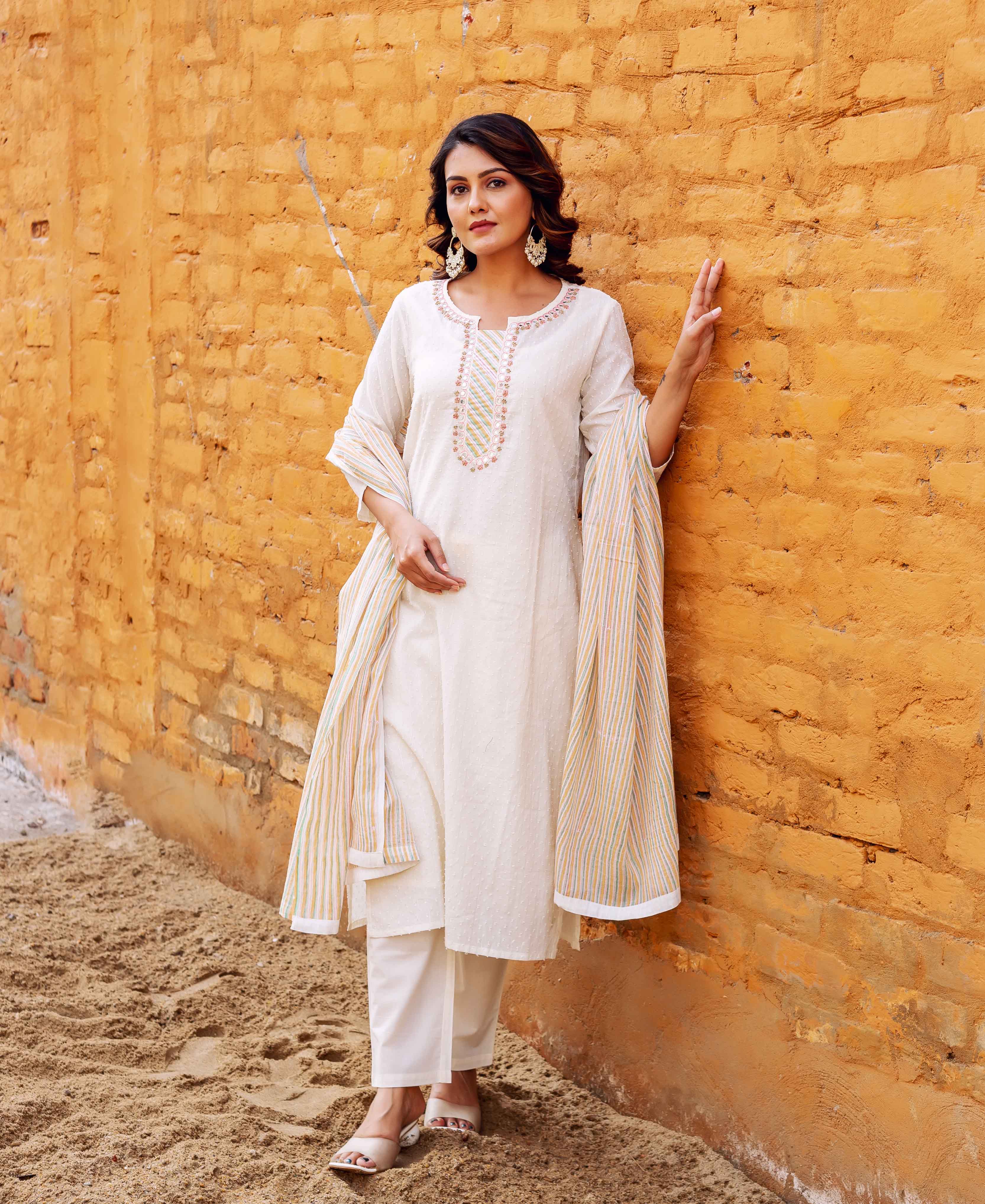 Model in ethnic lustrous ivory jacquard kurta set with embroidered neckline and striped dupatta.