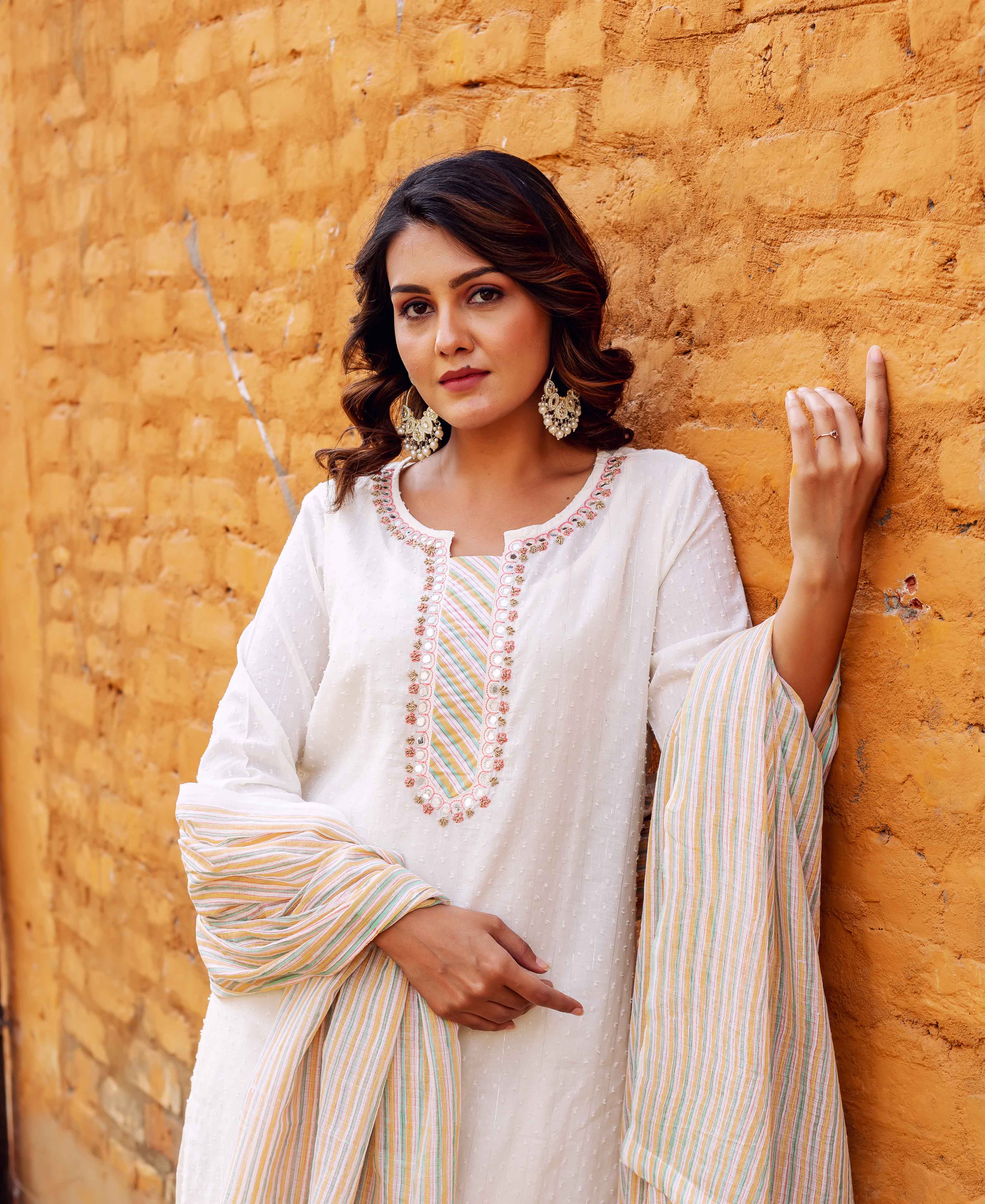 Woman in white textured kurta with vibrant embroidered neckline and multi-striped dupatta.