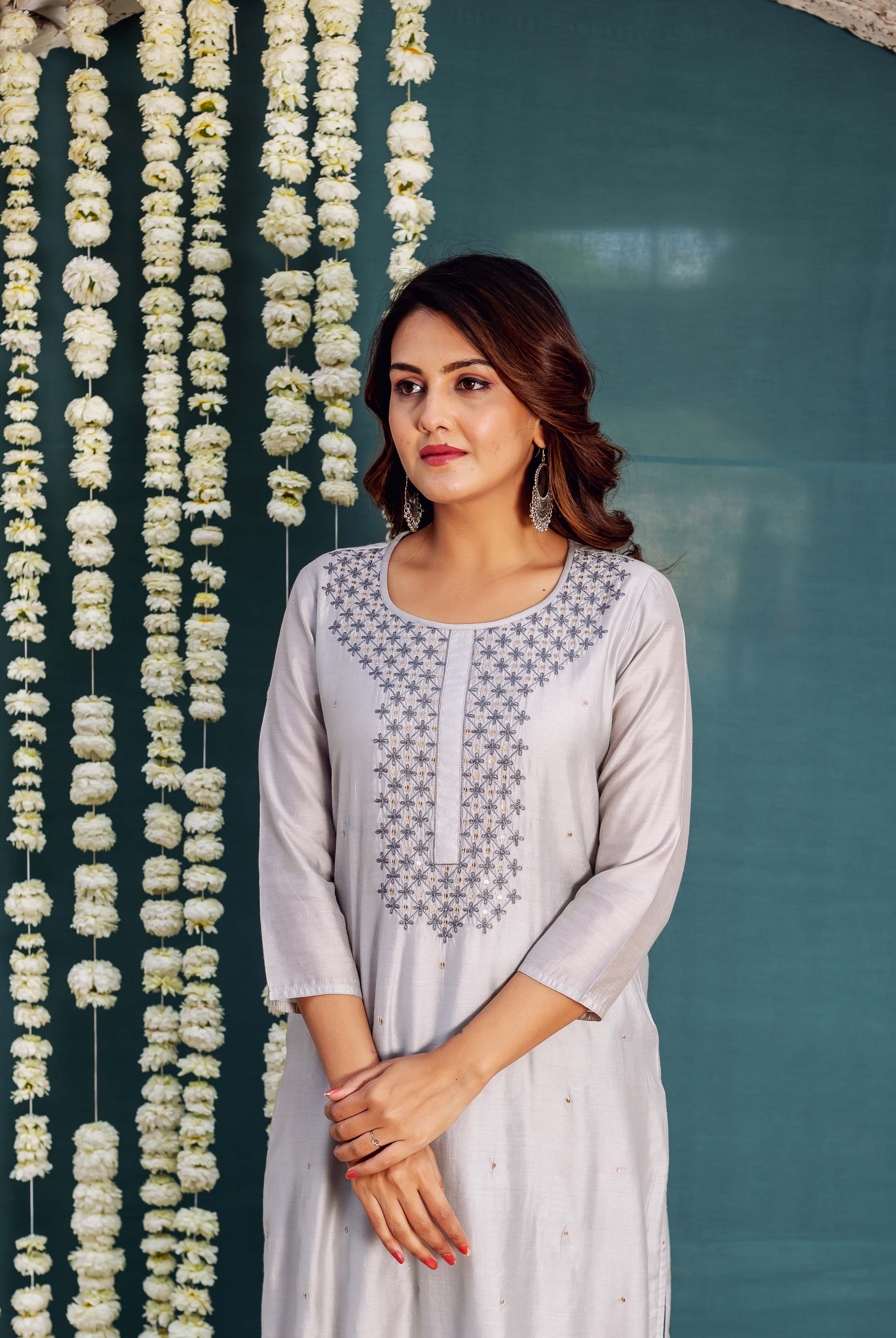Model wearing a light grey kurta with intricate dark grey and gold floral embroidered neckline.