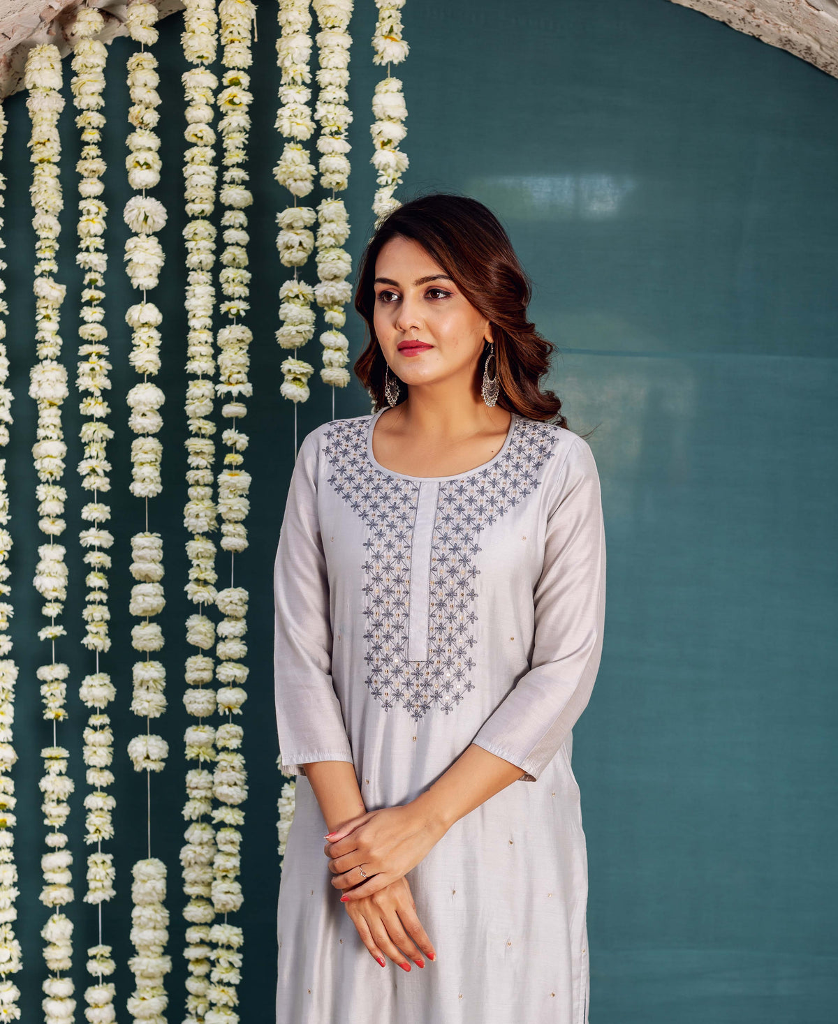 Model wearing a light grey kurta with intricate dark grey and gold floral embroidered neckline.
