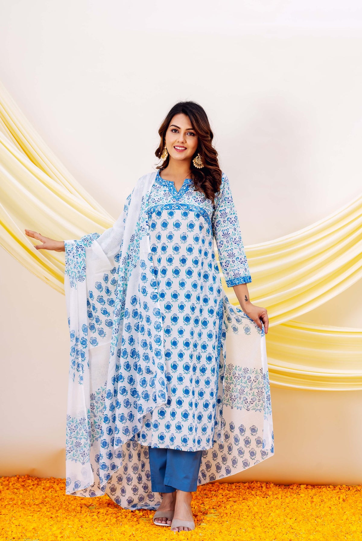 Woman in blue and white hand-block-printed cotton kurta with floral patterns and yellow drapes.