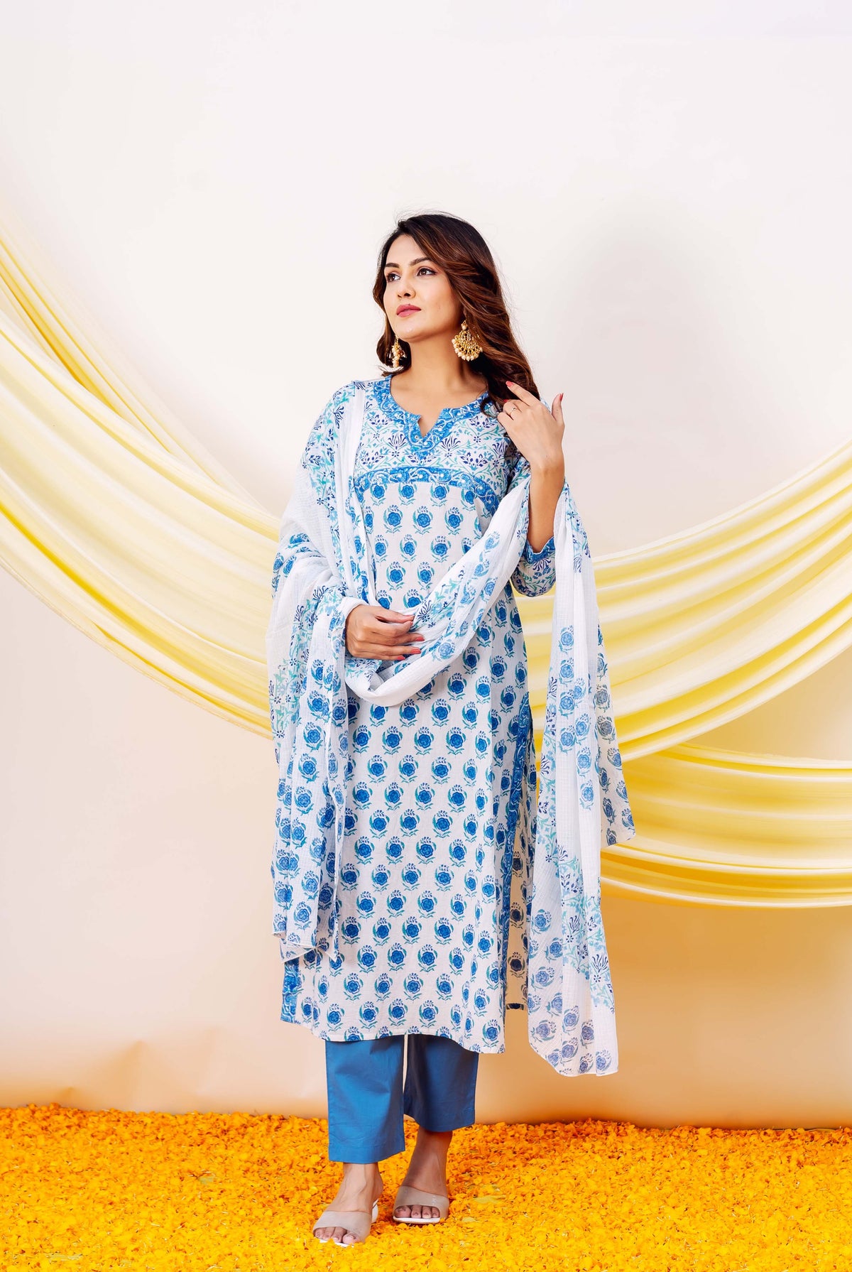 Woman wearing white and blue hand-block-printed cotton kurta with floral patterns and blue pants.