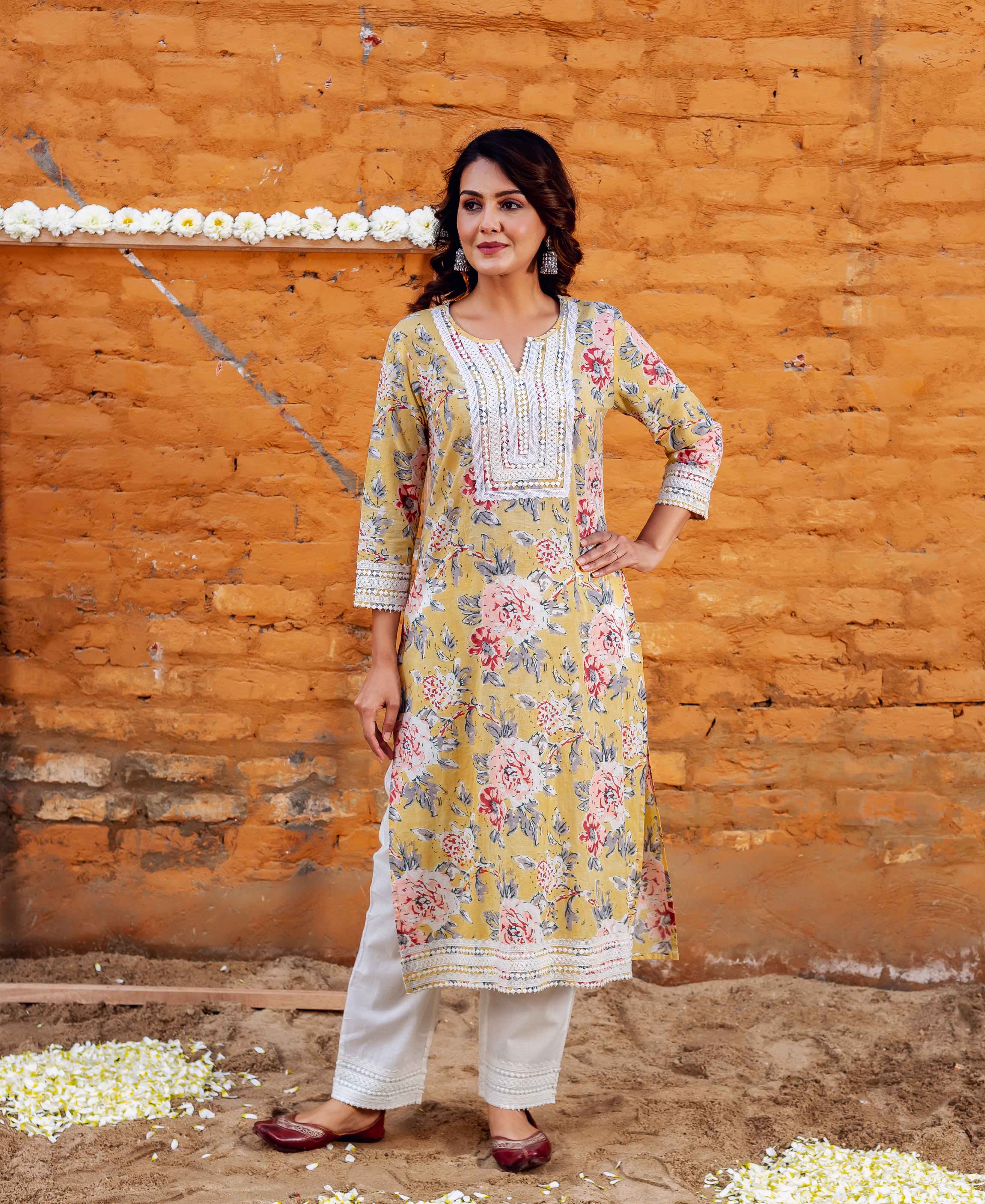 Woman in yellow kurta with pink & white floral block print, white lace, and white pants.