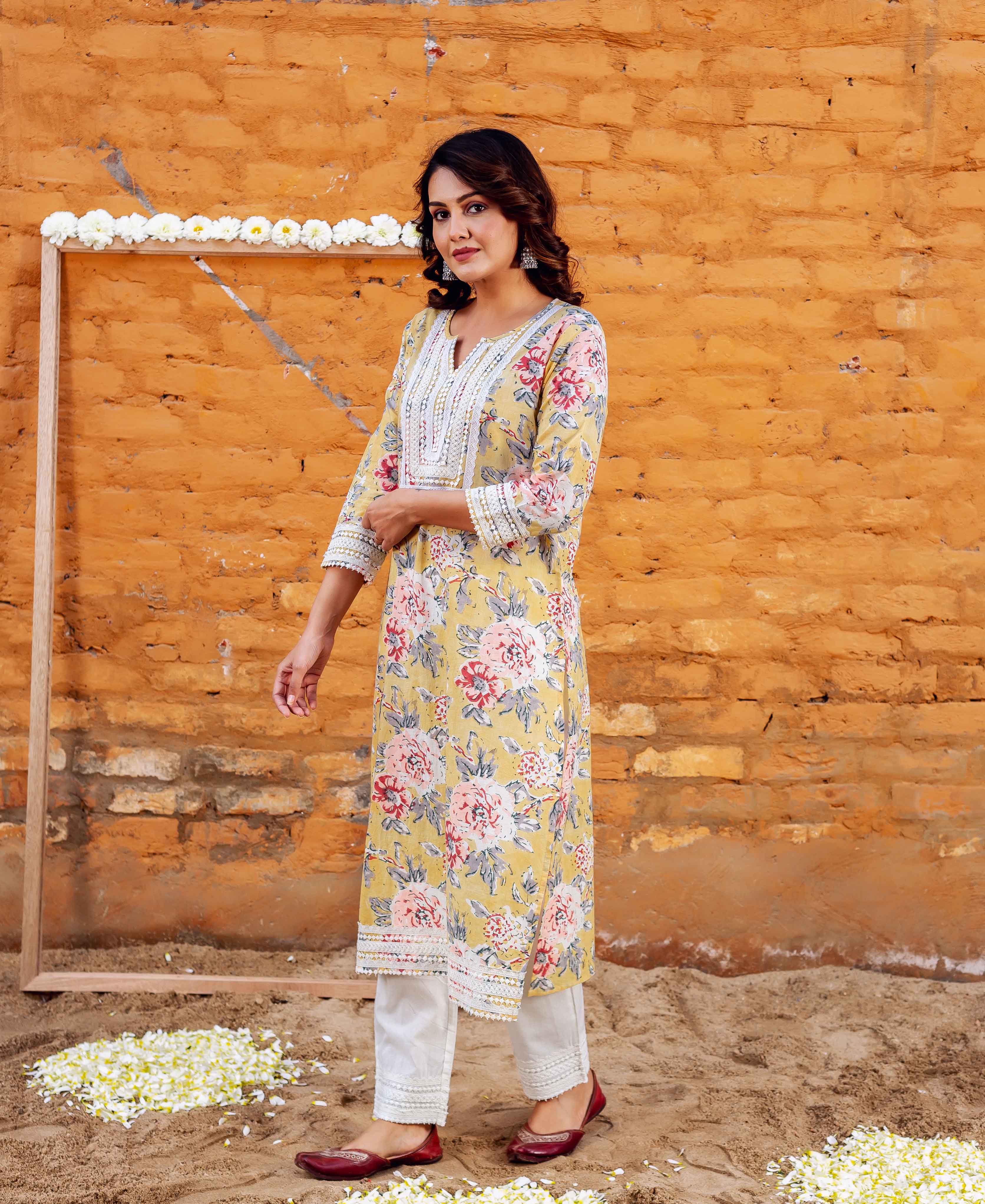 Model wearing a sunflower yellow floral block printed kurta with white lace trim and white pants.