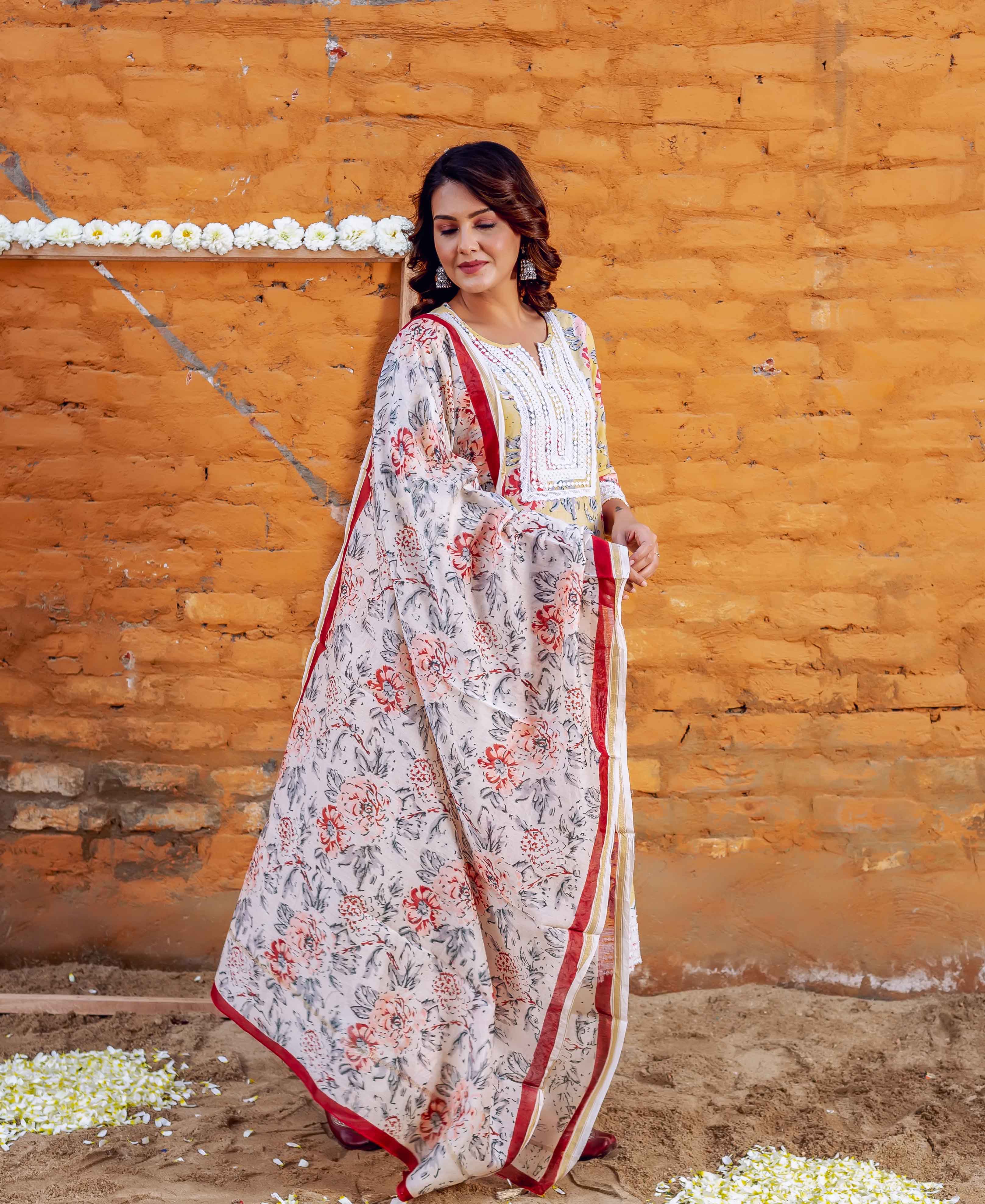 Model in a cream floral block printed kurta and dupatta set with red borders.
