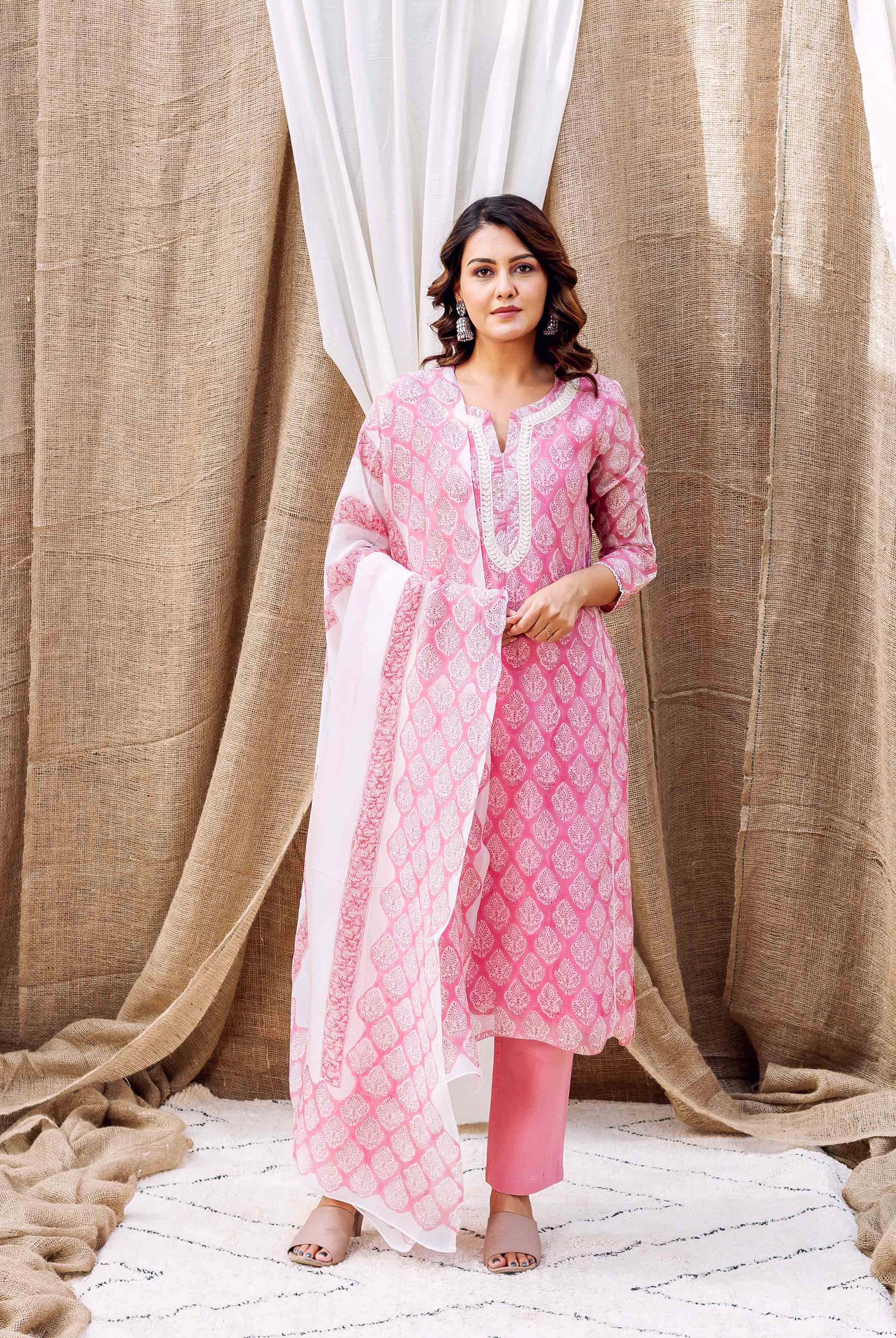 Woman wears blush pink printed kurta set with leaf motifs and matching white dupatta.