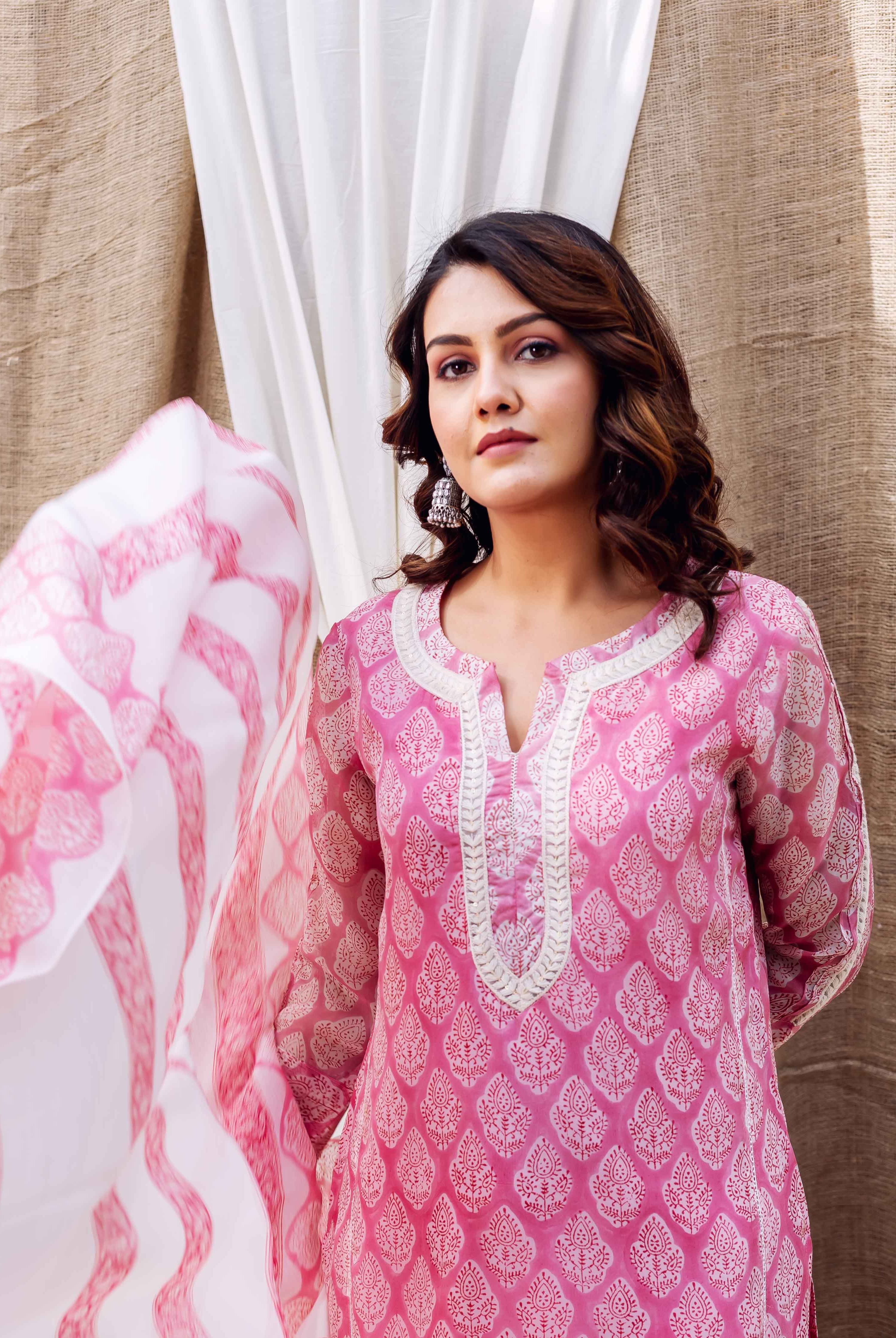 Woman in blush pink hand-block-printed kurta with white neck trim, flowing matching dupatta.