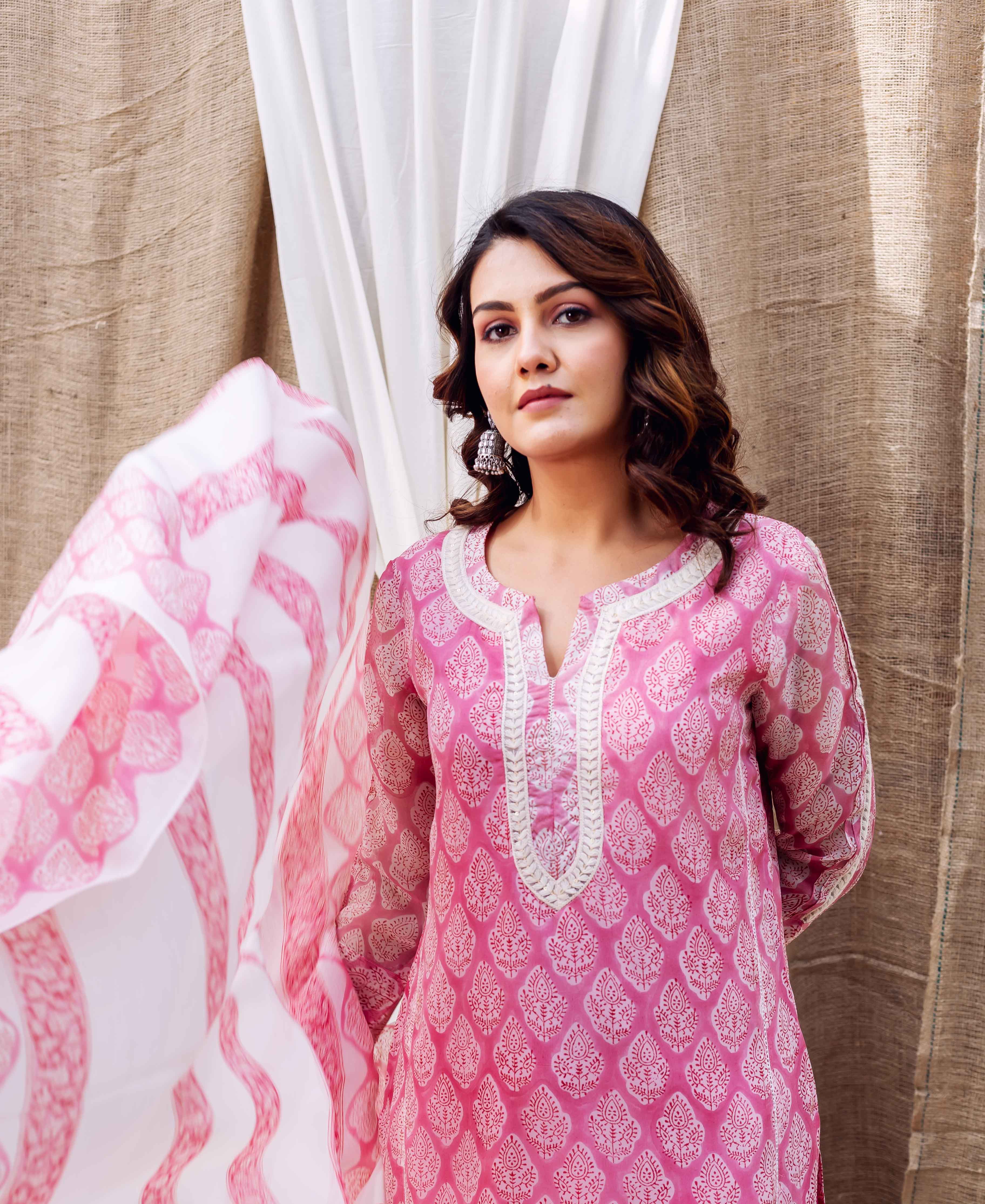 Woman in blush pink hand-block-printed kurta with white neck trim, flowing matching dupatta.