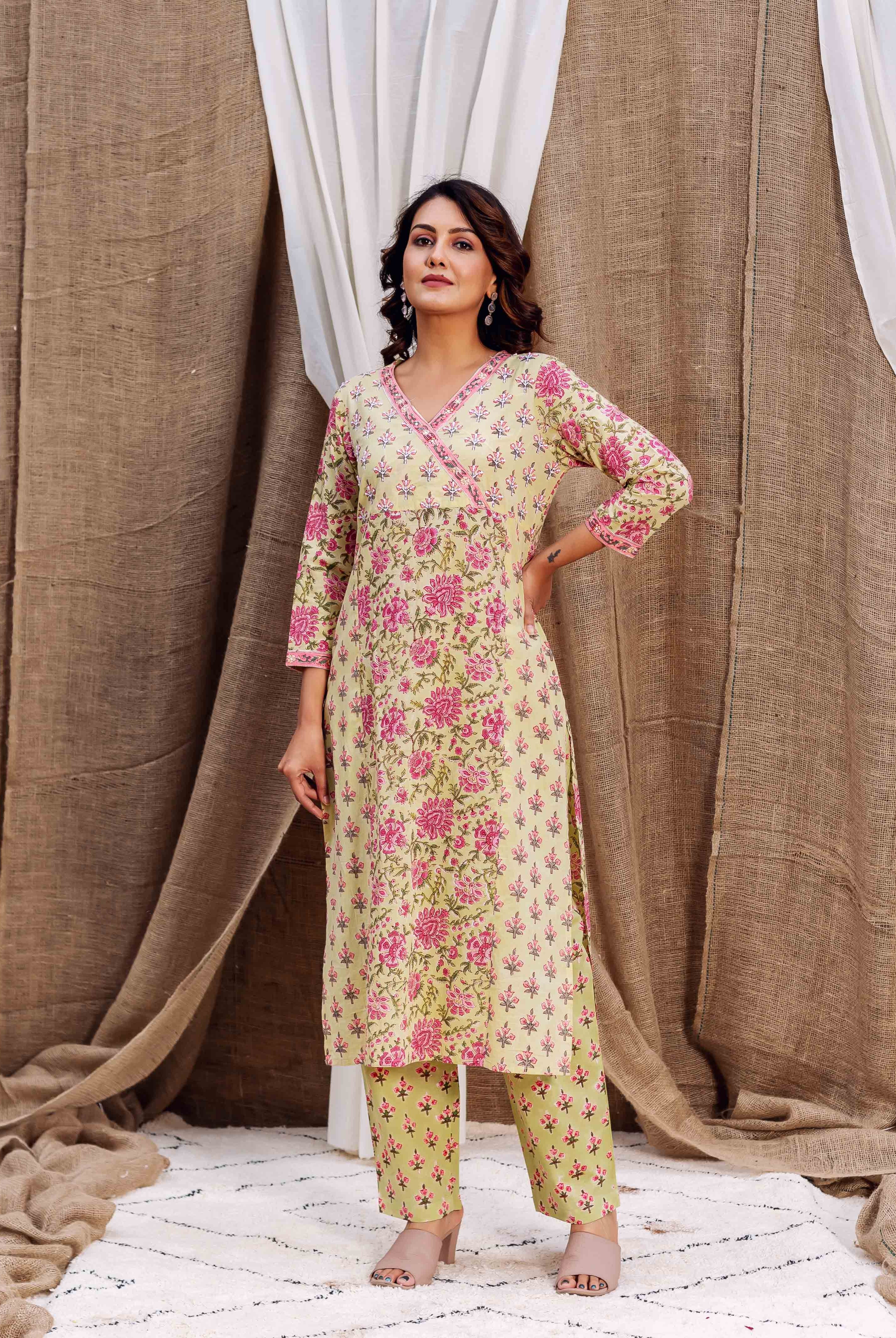 Woman wearing pale yellow kurta with pink floral print and matching trousers, beige heels.