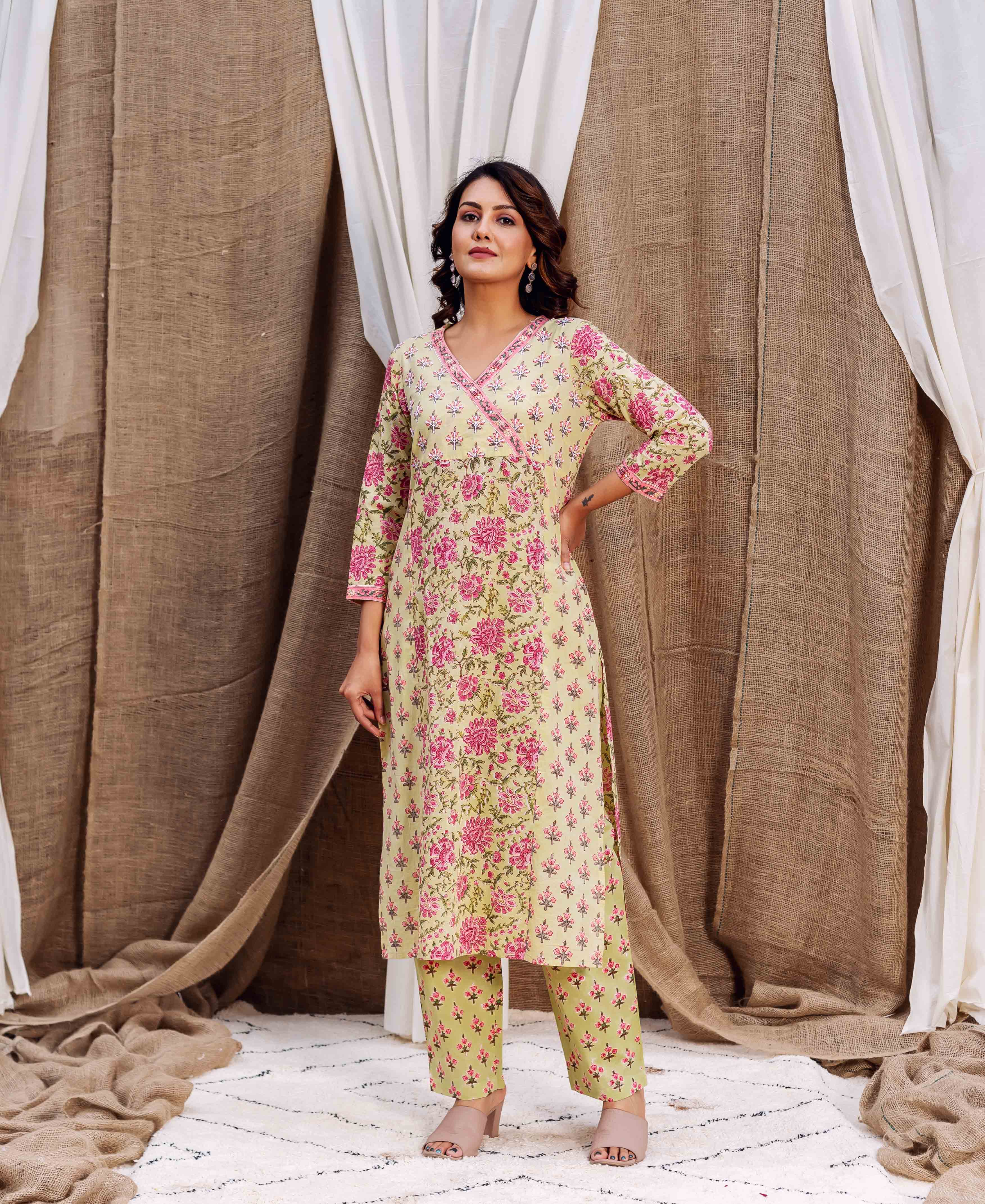 Woman wearing pale yellow kurta with pink floral print and matching trousers, beige heels.
