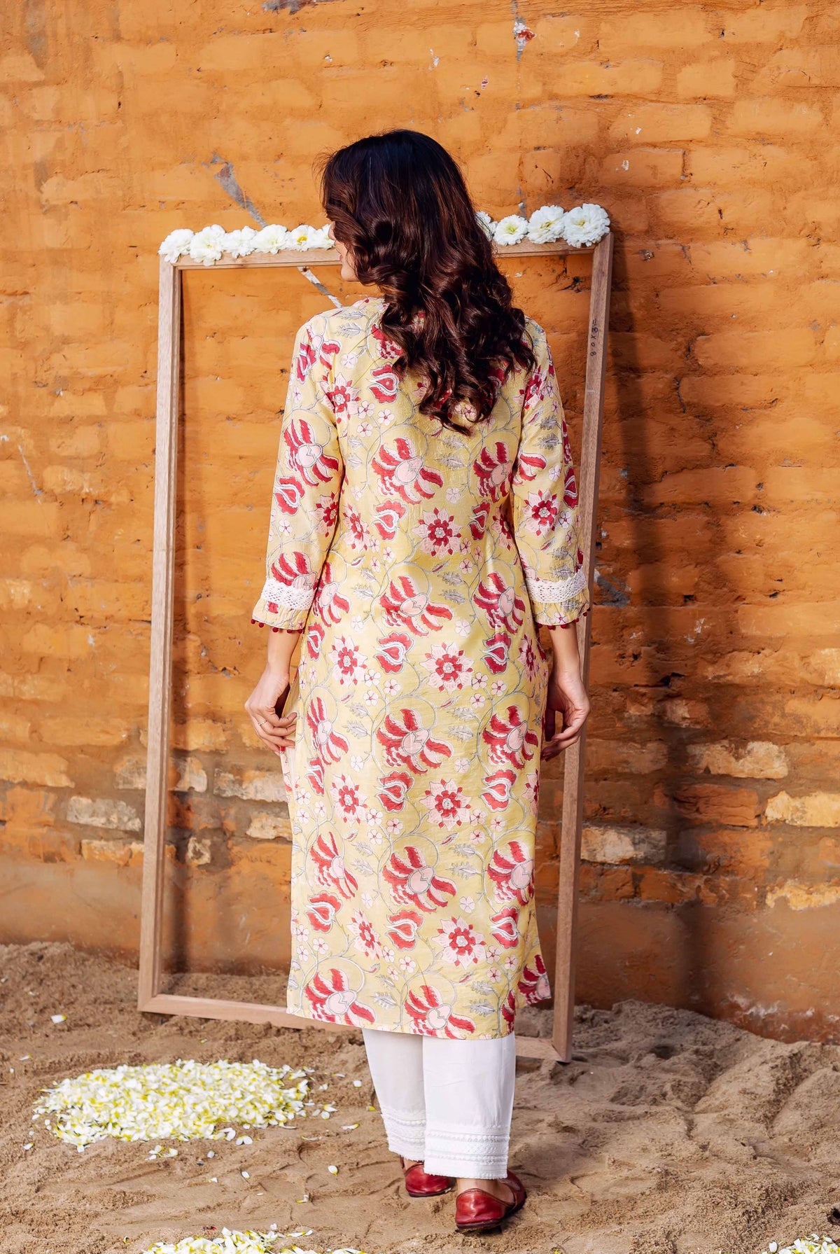 Model from back wearing a yellow Chanderi kurta with red hand-block printed floral motifs.