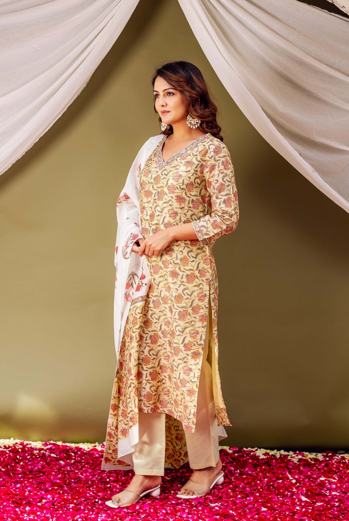 On a model, side view of a light yellow kurta with red and green floral block print.