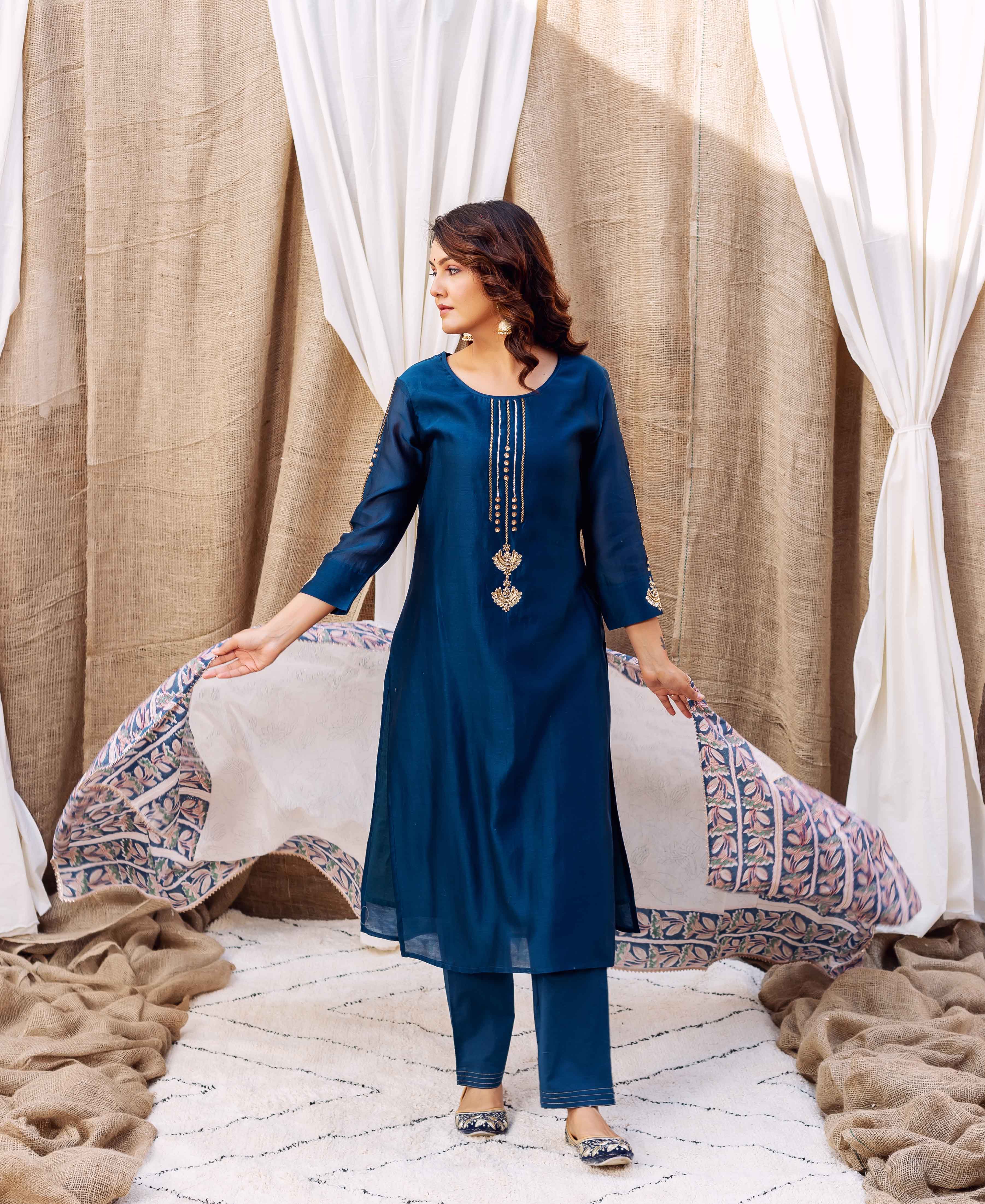 Model in a deep blue embroidered kurta set, holding a detailed hand-block printed dupatta.