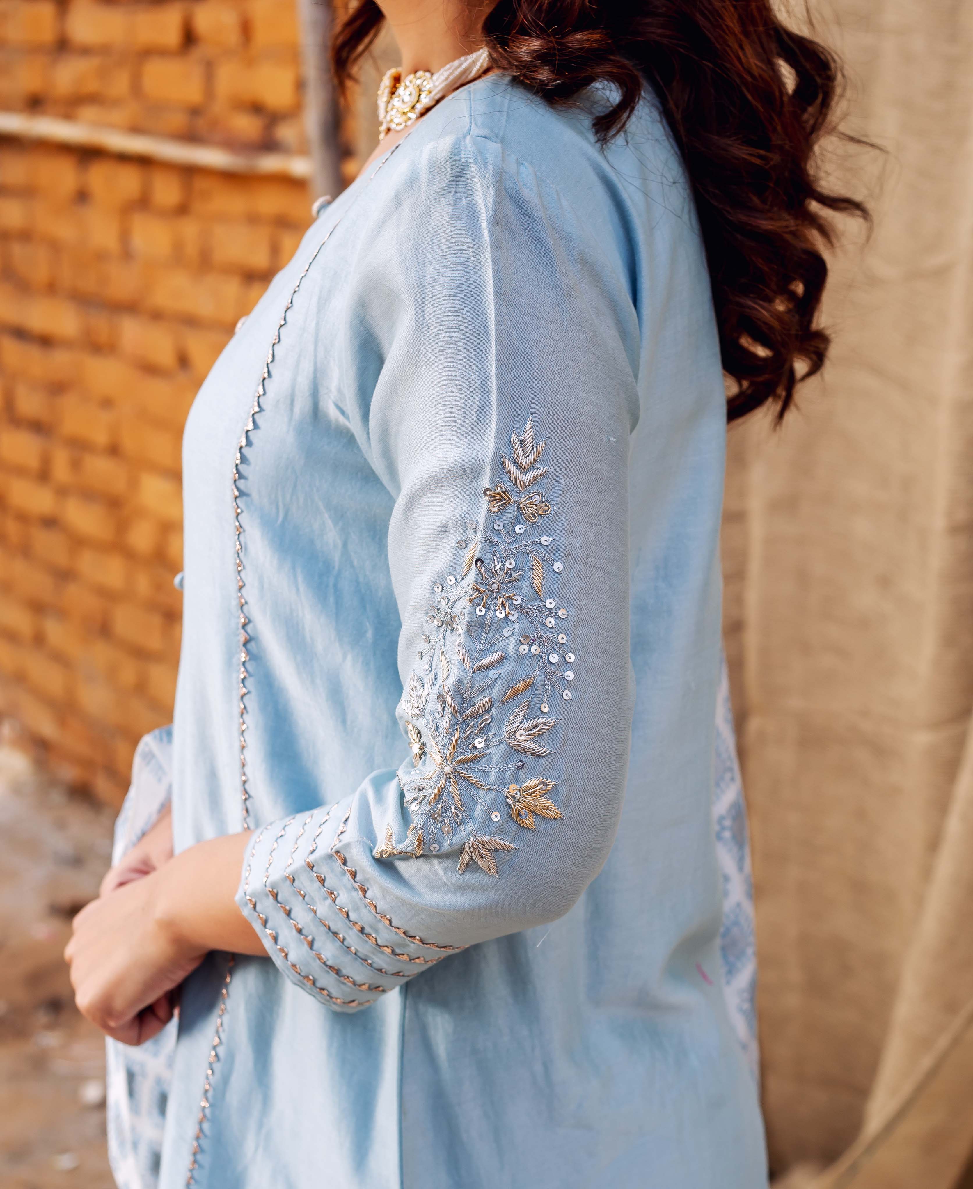 Side view of model in azure kurta with embroidered sleeve and subtle patterned print.