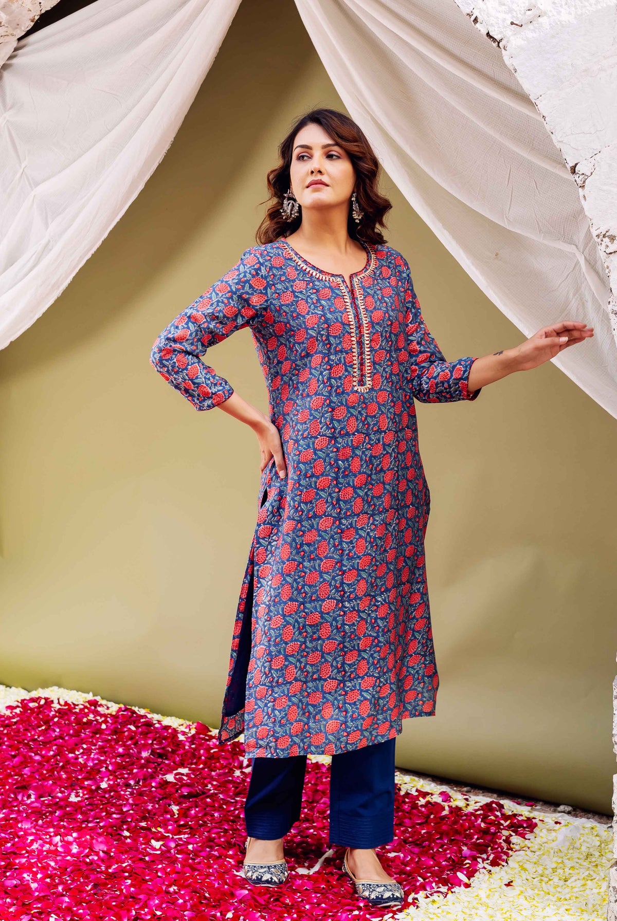 Front view of model wearing blue kurta with red floral print and gota yoke, blue pants.
