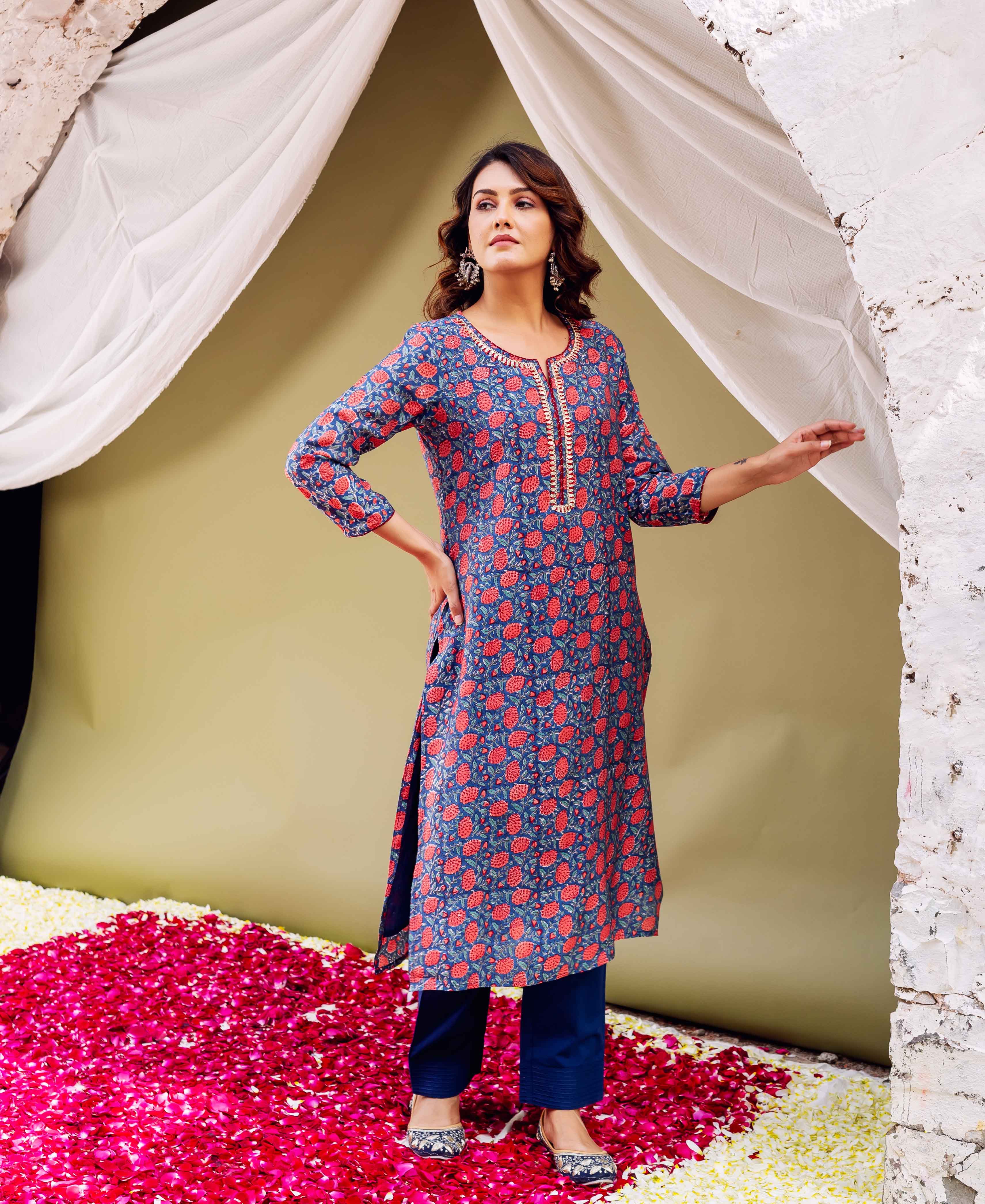 Front view of model wearing blue kurta with red floral print and gota yoke, blue pants.