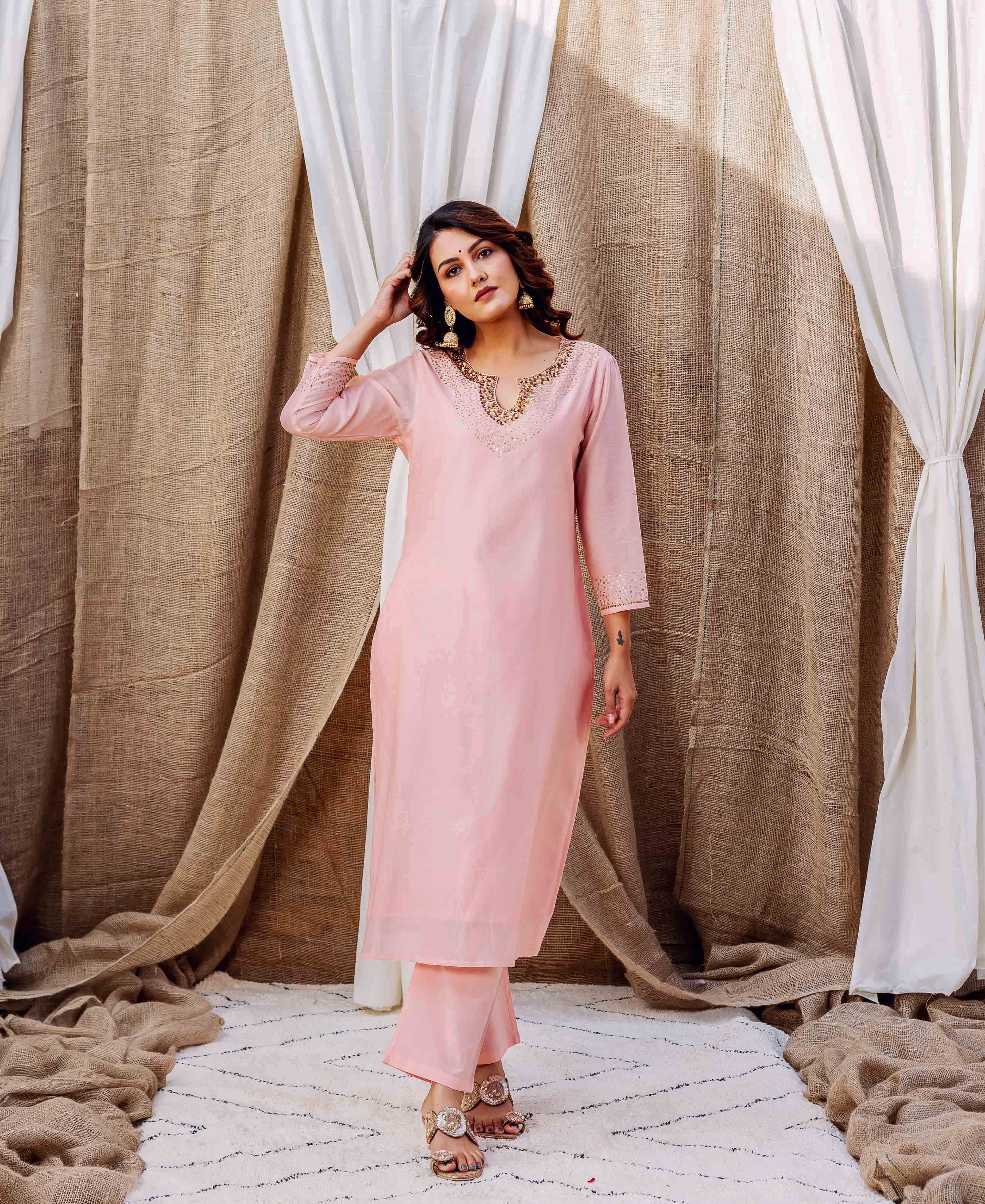 Full-length shot of standing model in soft pink kurta set with golden embellished V-neck and sleeves.