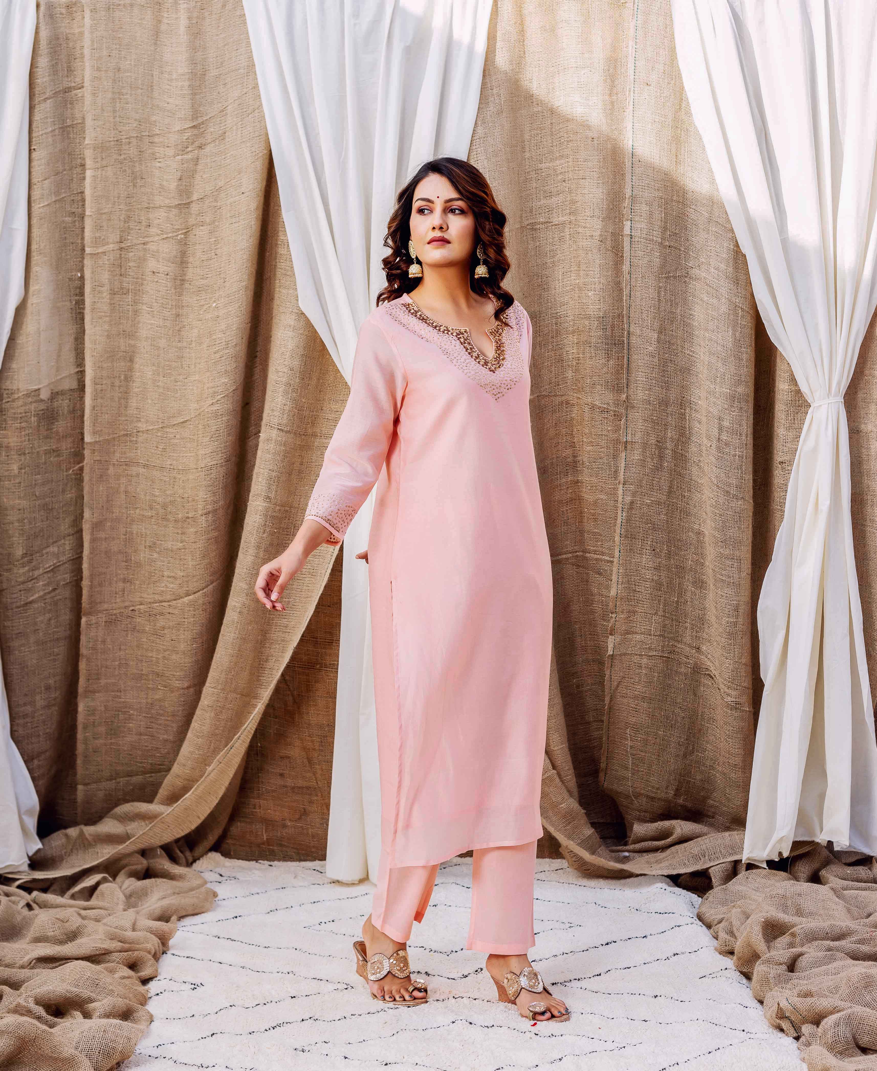 Model in a rose pink kurta set with intricate golden embroidered V-neckline and cuffs.