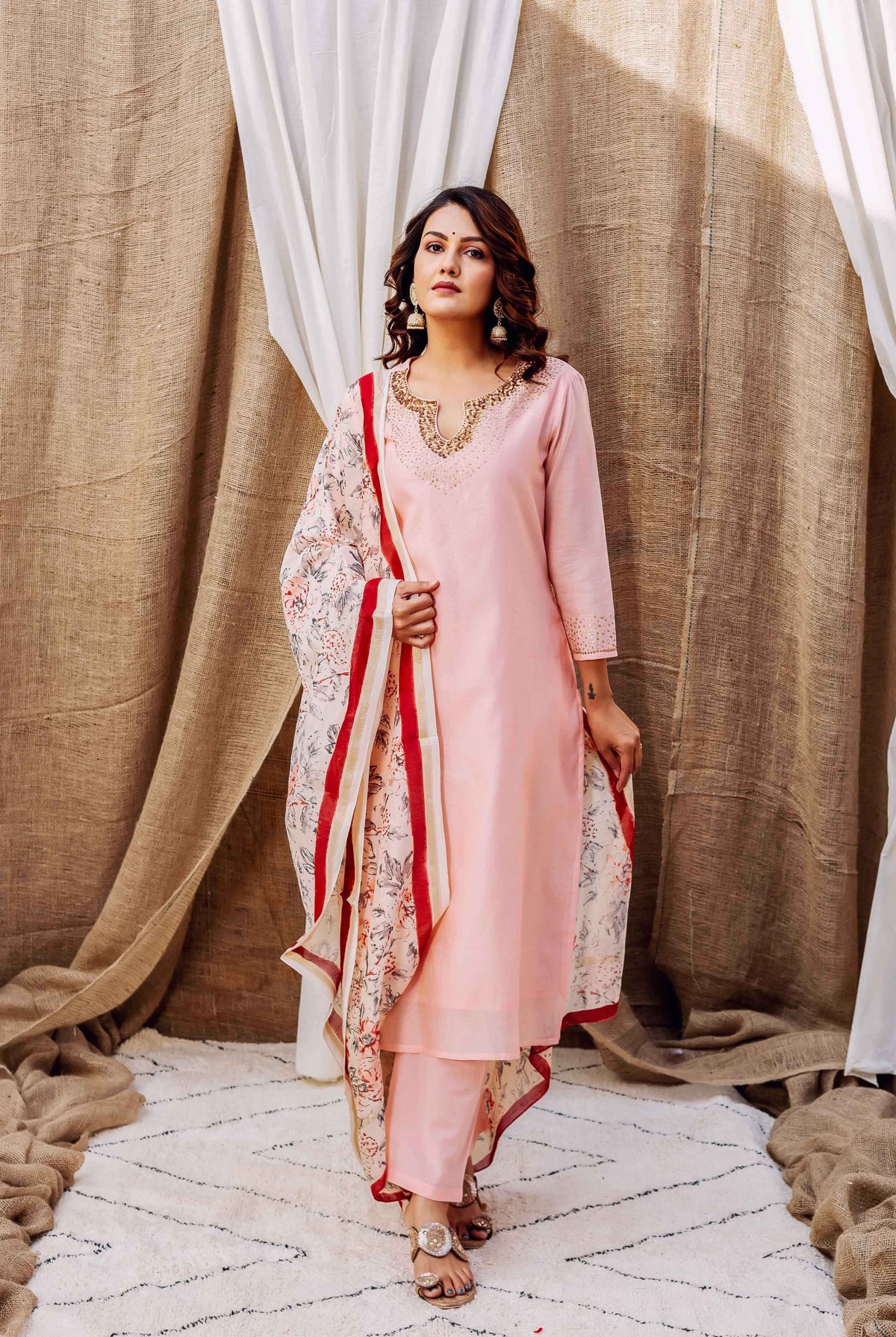 On a model, a rose pink kurta set featuring an embroidered neck and floral printed dupatta.