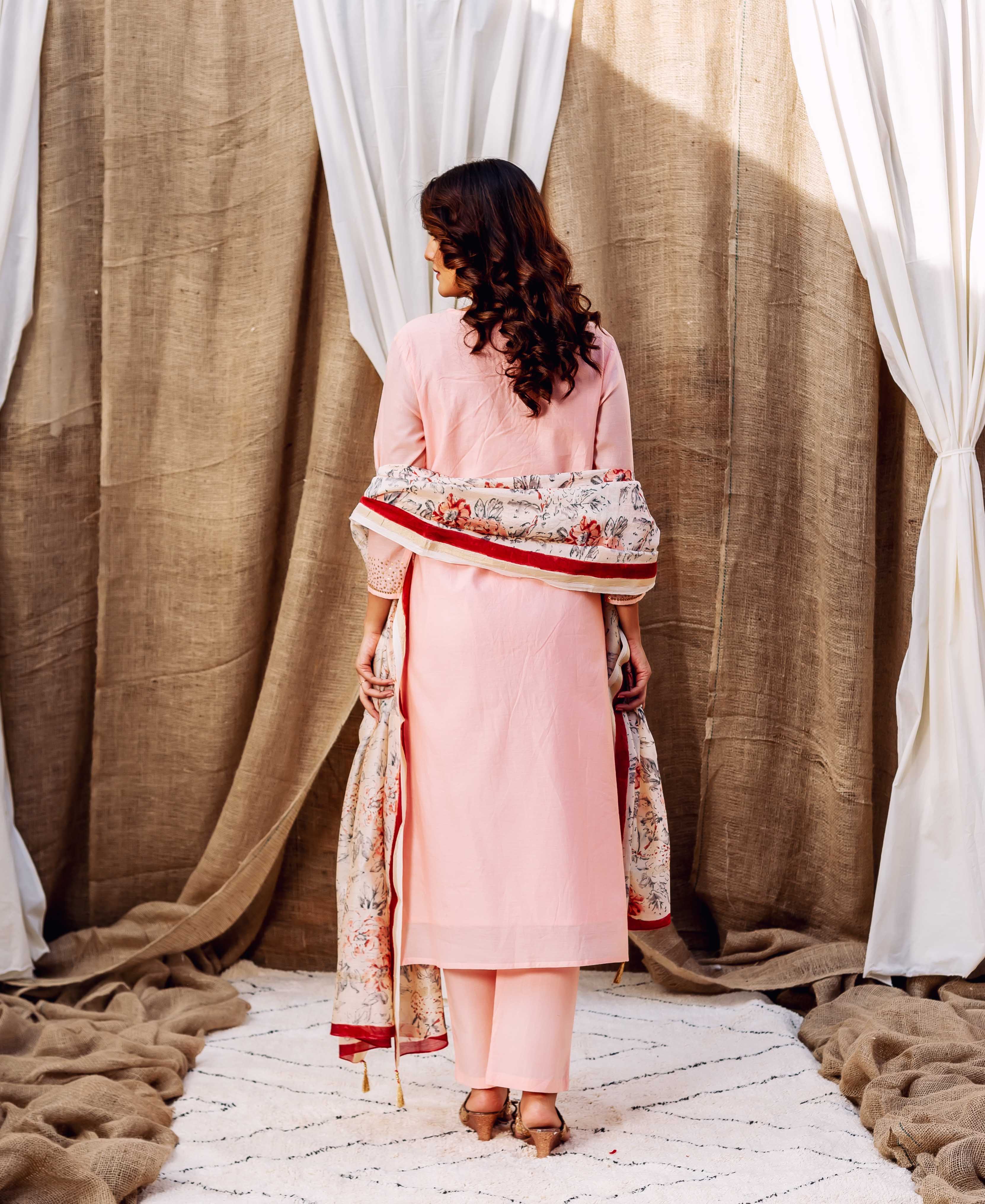 Back view of a model wearing a rose pink kurta set with a patterned floral dupatta.