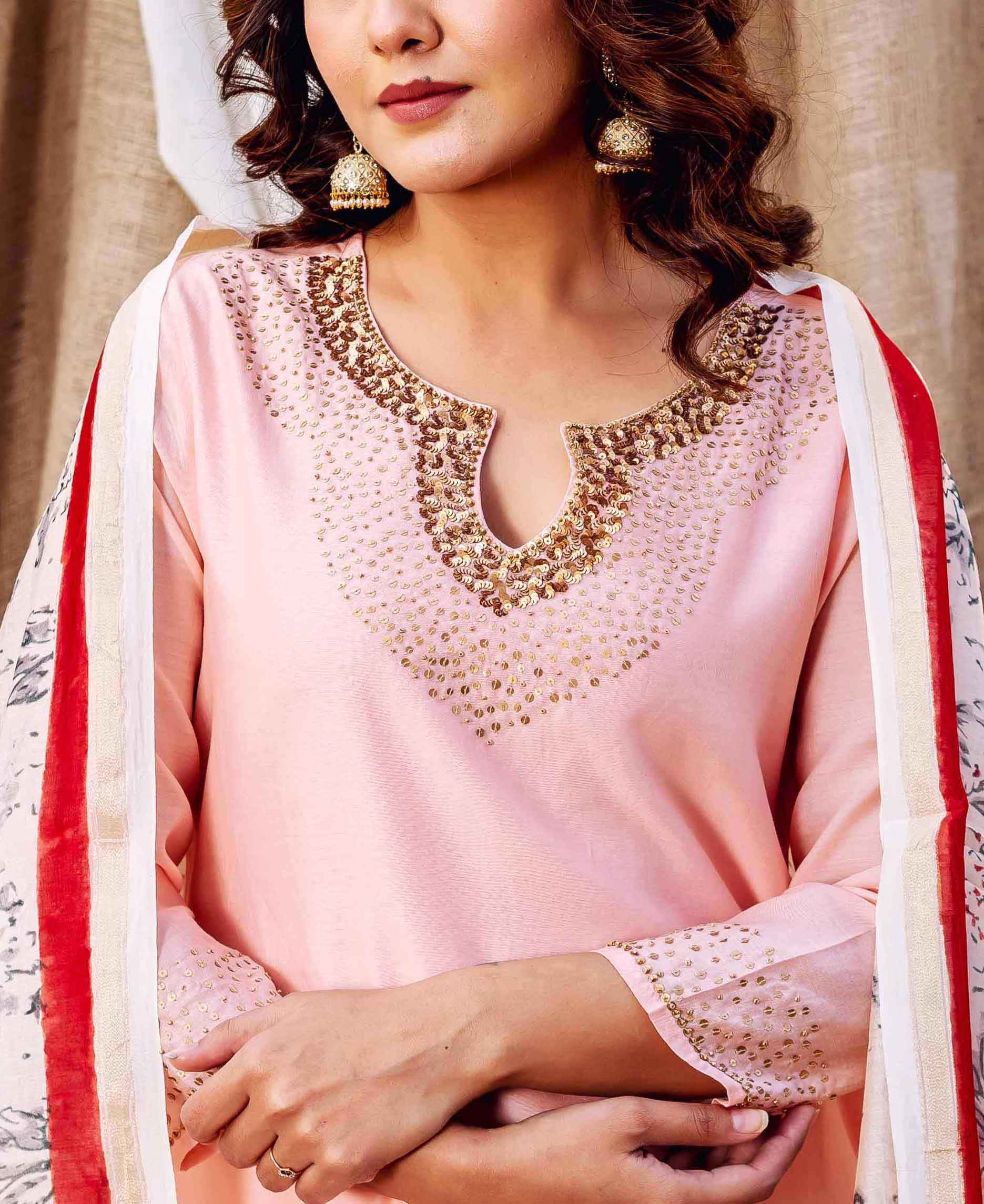 Model wears rose pink kurta with golden embellished neckline and a printed dupatta.