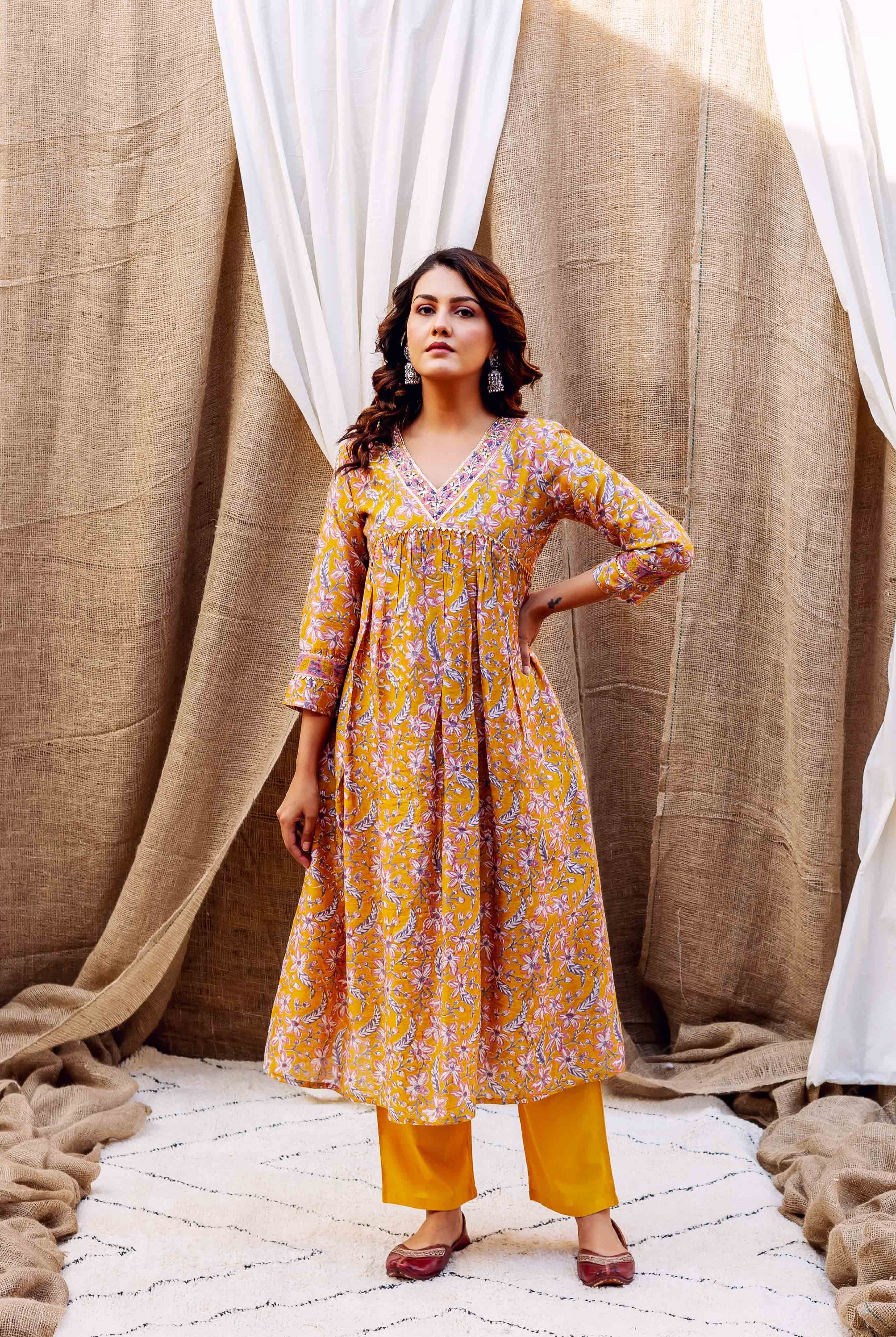 Front view of a model in a golden yellow floral block-printed kurta set with V-neck.