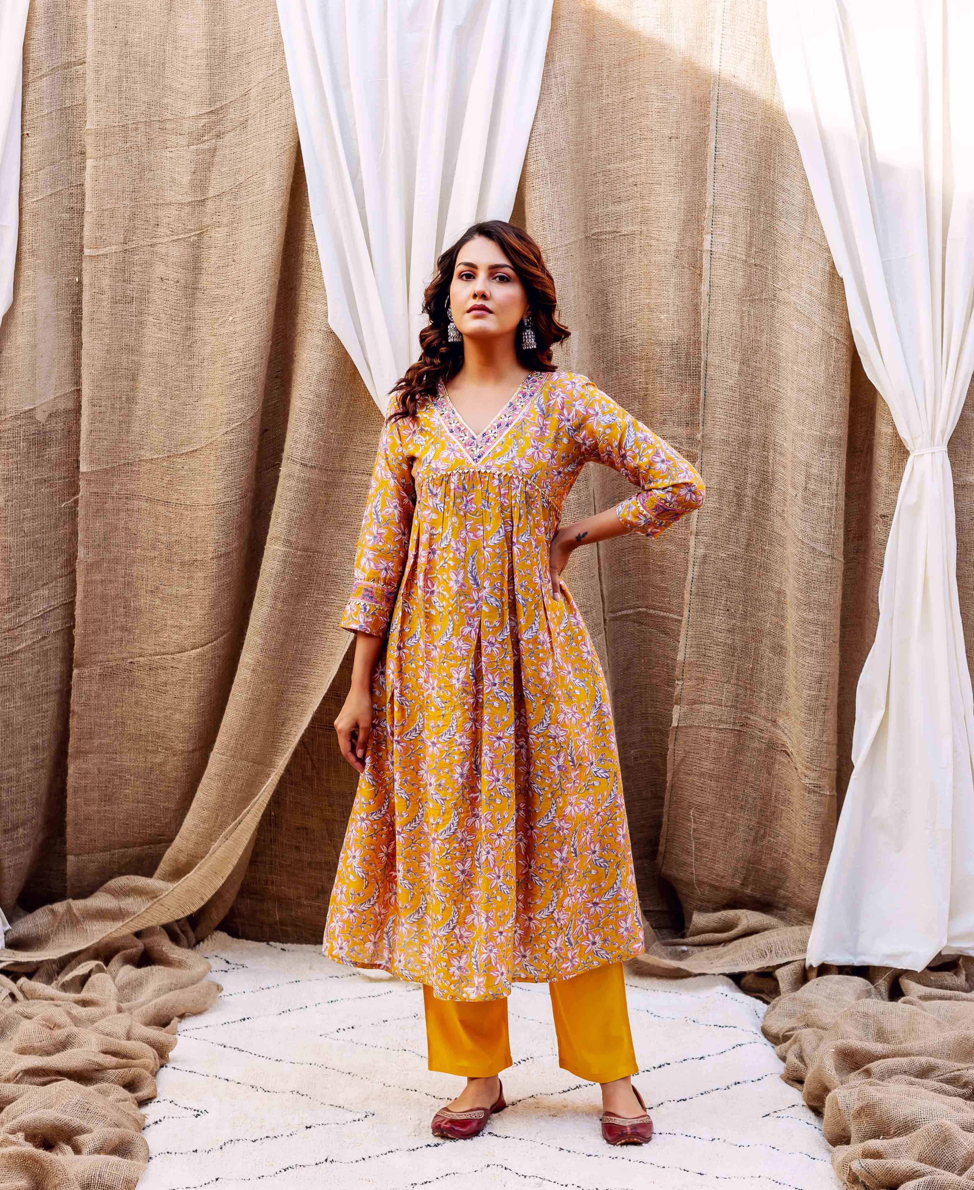 Front view of a model in a golden yellow floral block-printed kurta set with V-neck.