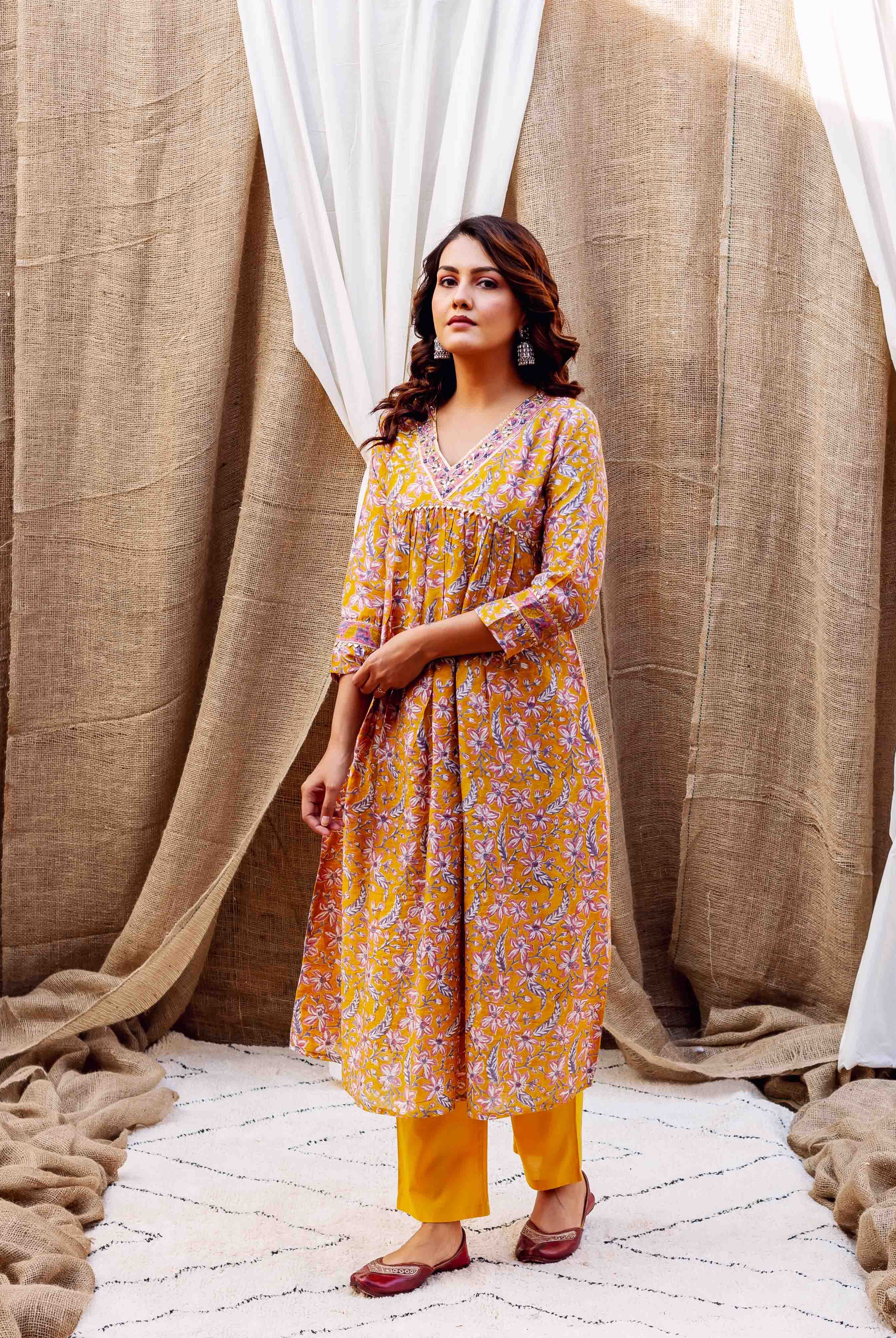 Front full-length view of model in golden spice floral block printed kurta with yellow pants.