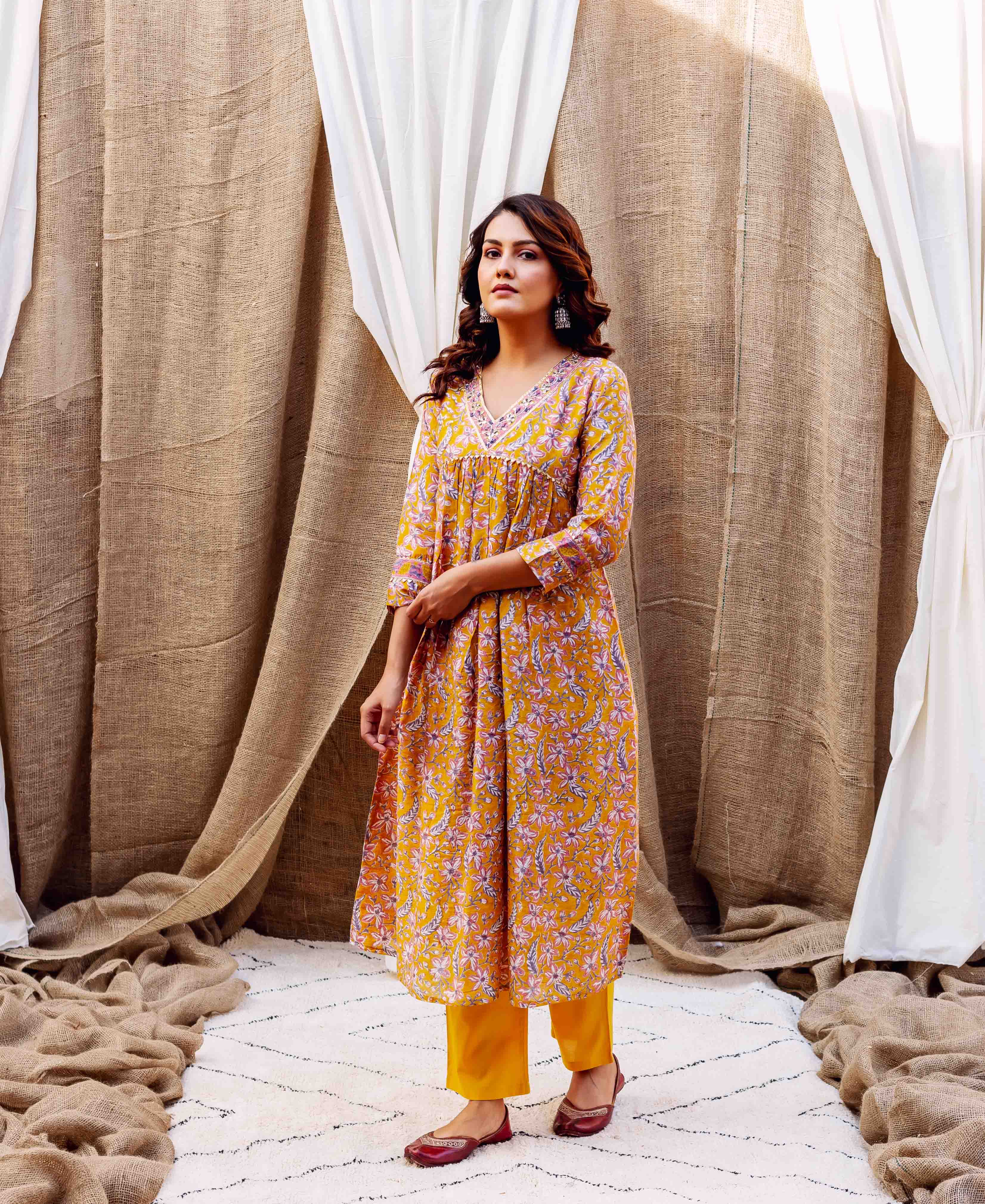 Front full-length view of model in golden spice floral block printed kurta with yellow pants.