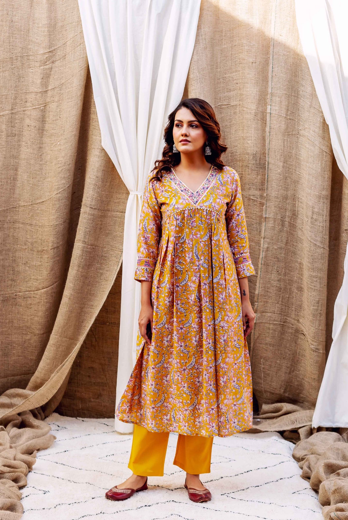 Model in golden yellow floral block printed Chanderi kurta, matching pants, and maroon flats.