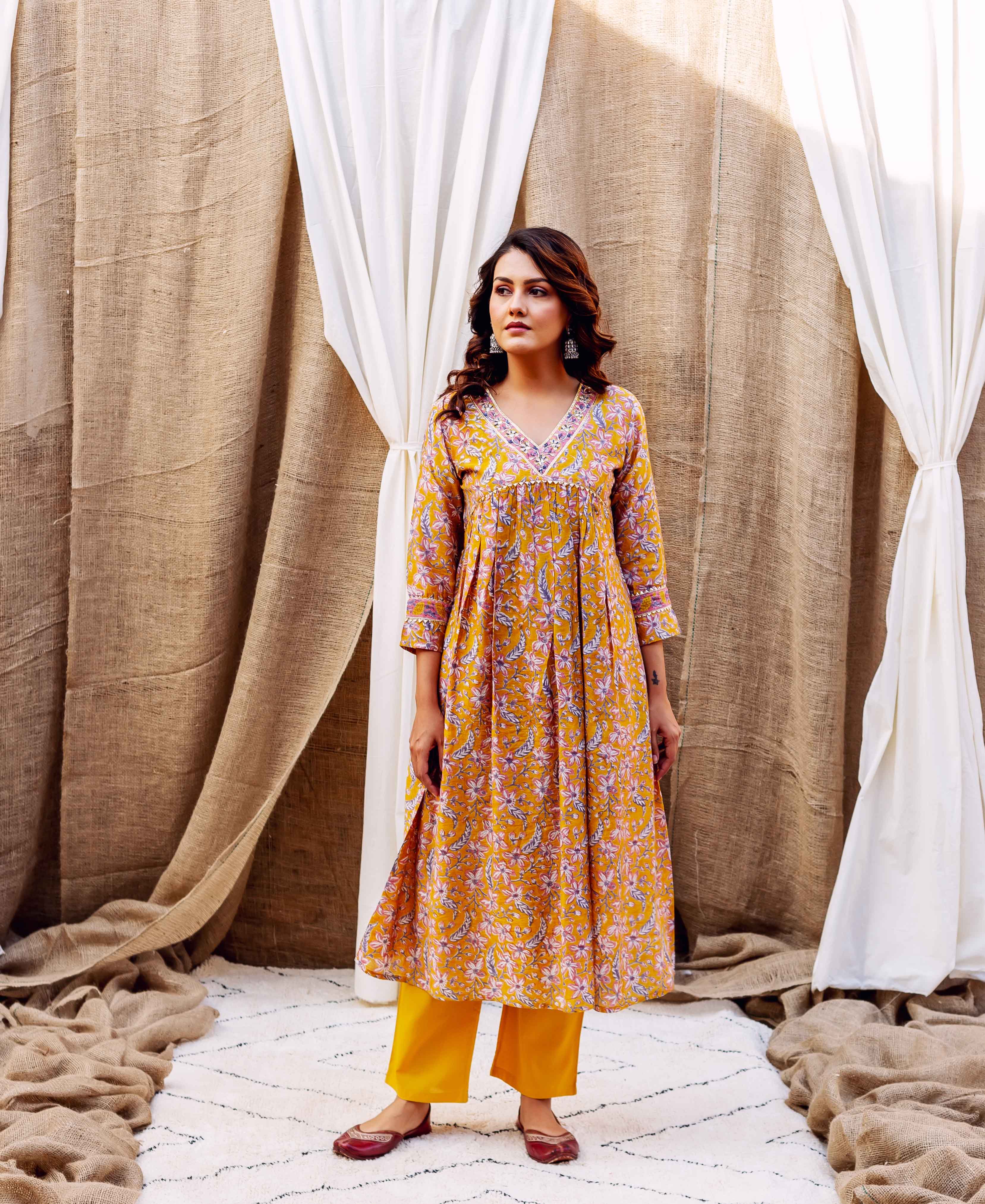 Model in golden yellow floral block printed Chanderi kurta, matching pants, and maroon flats.
