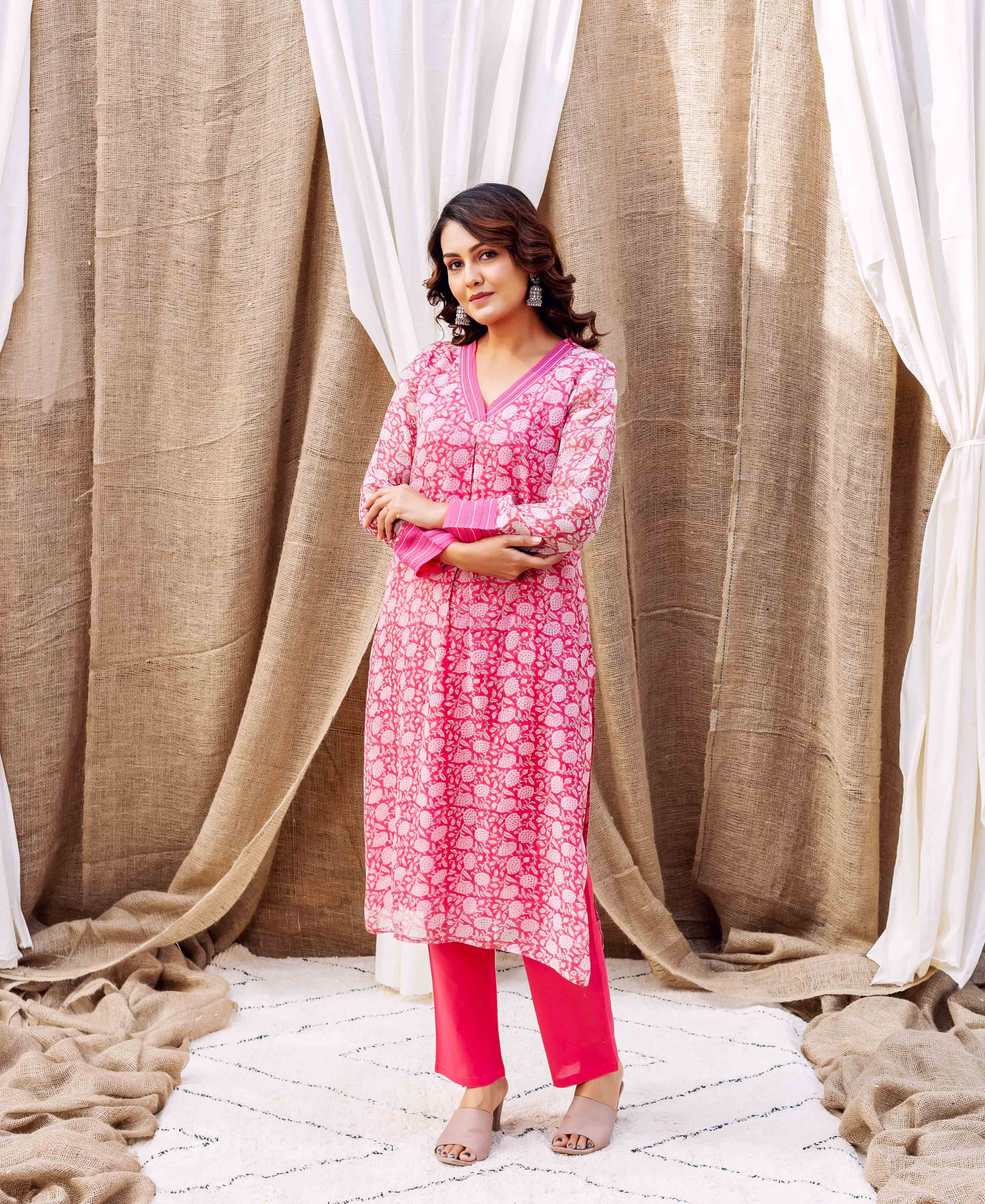 Full-body shot of model wearing pink floral hand-printed kurta and matching pants.