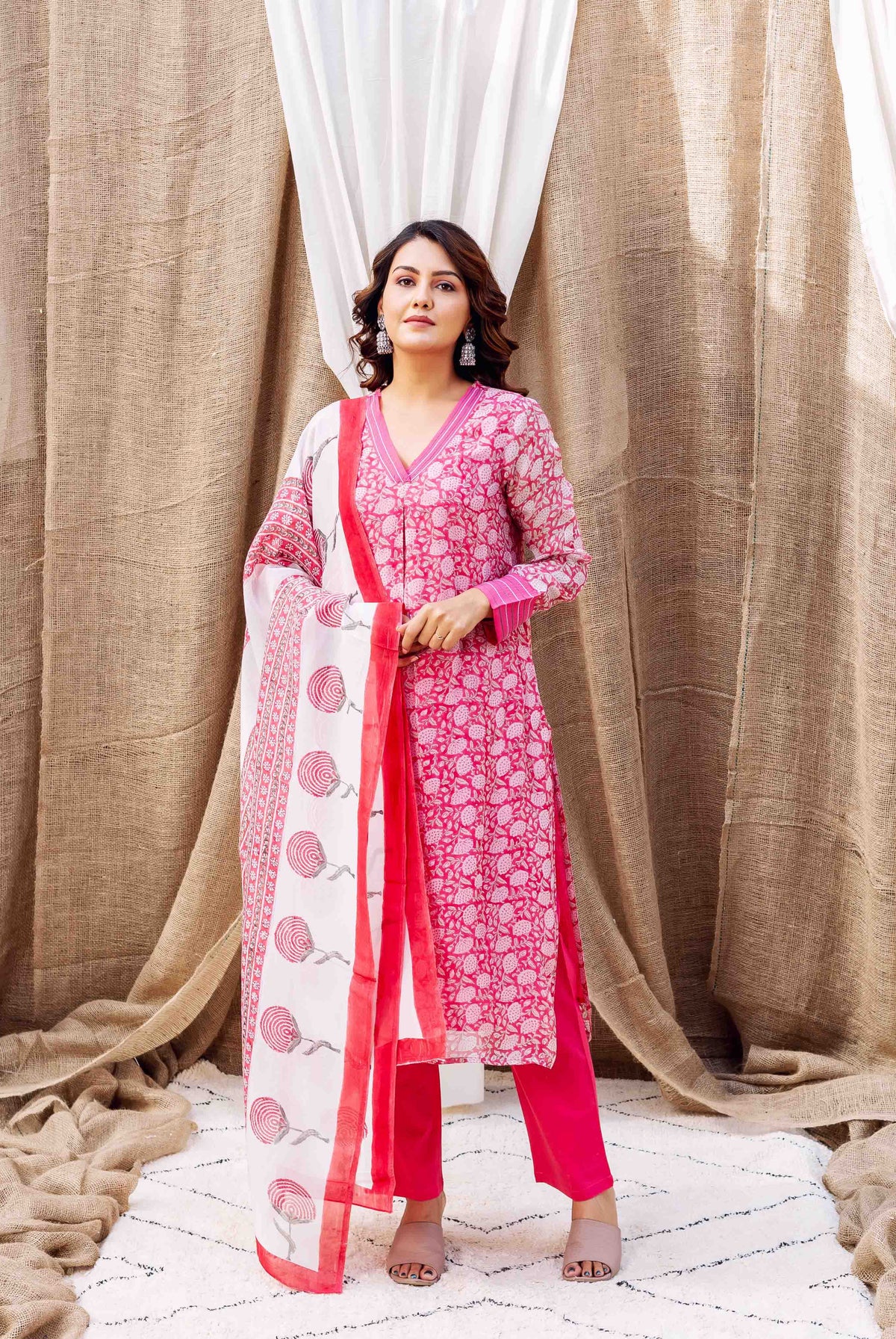 Full-length model in pink hand-block printed floral kurta set with white dupatta.