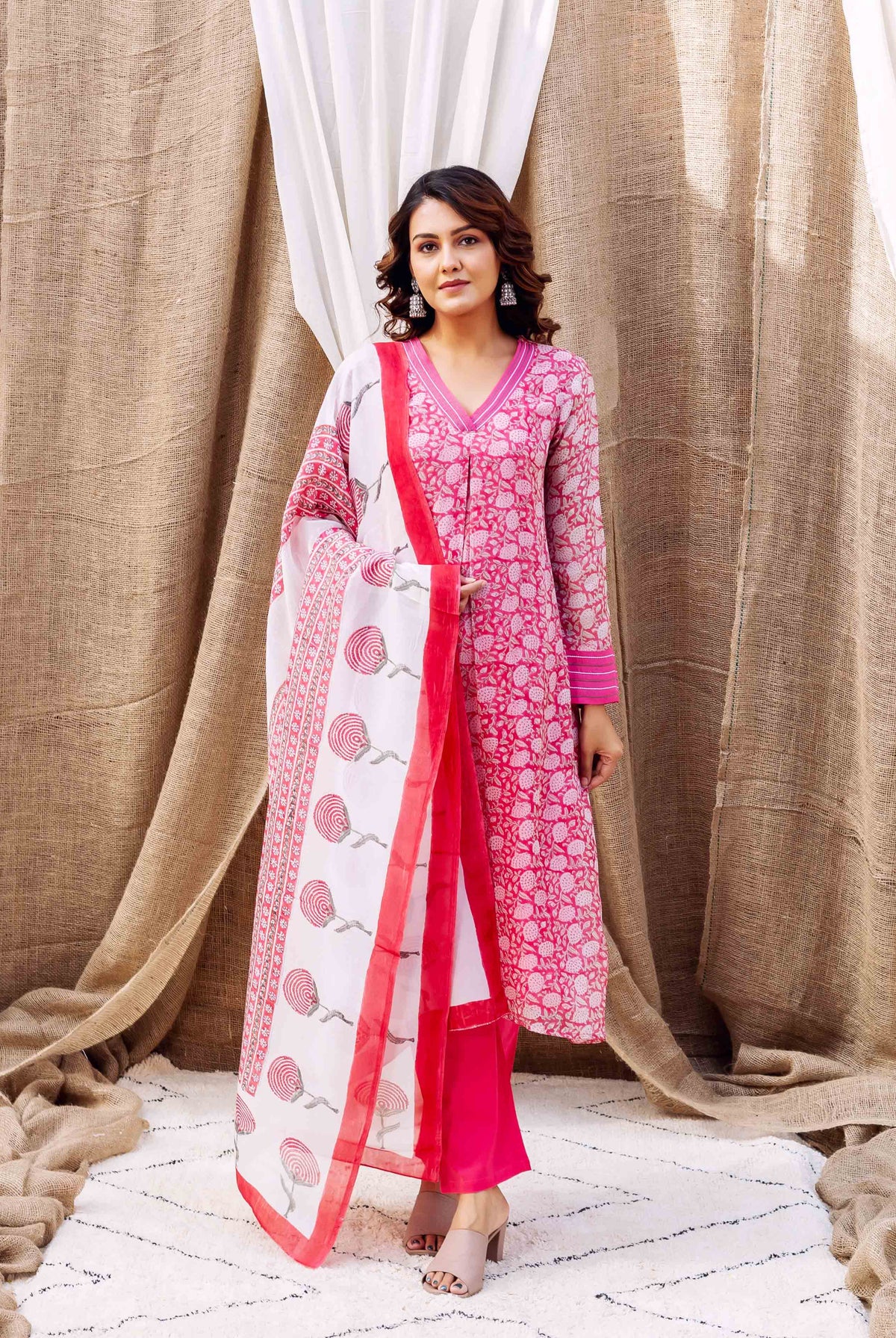 On a model, full shot, wearing a pink hand-block printed kurta set with white patterned dupatta.