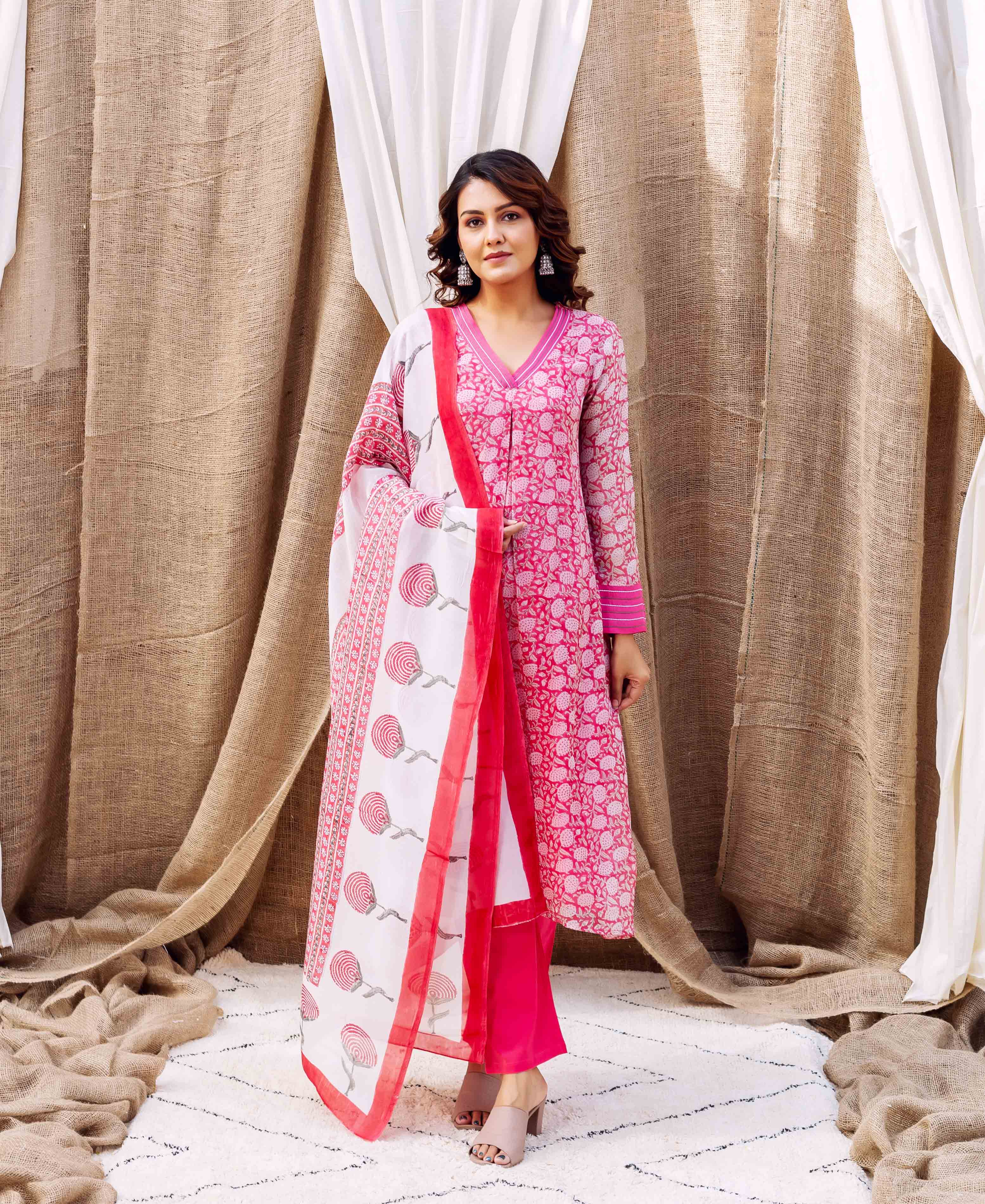 On a model, full shot, wearing a pink hand-block printed kurta set with white patterned dupatta.