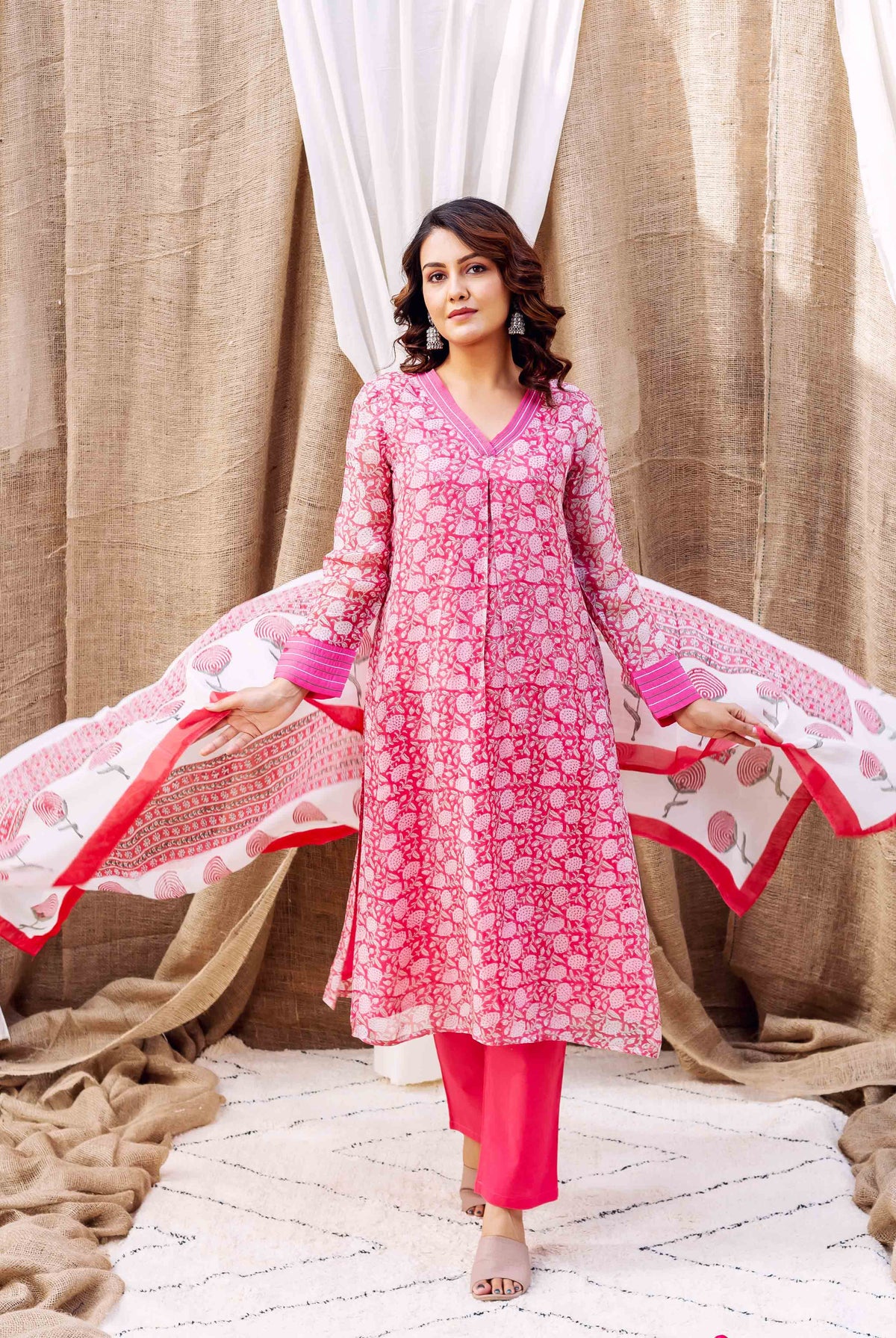 Frontal shot of model in pink hand-printed floral kurta set with flowing white dupatta.